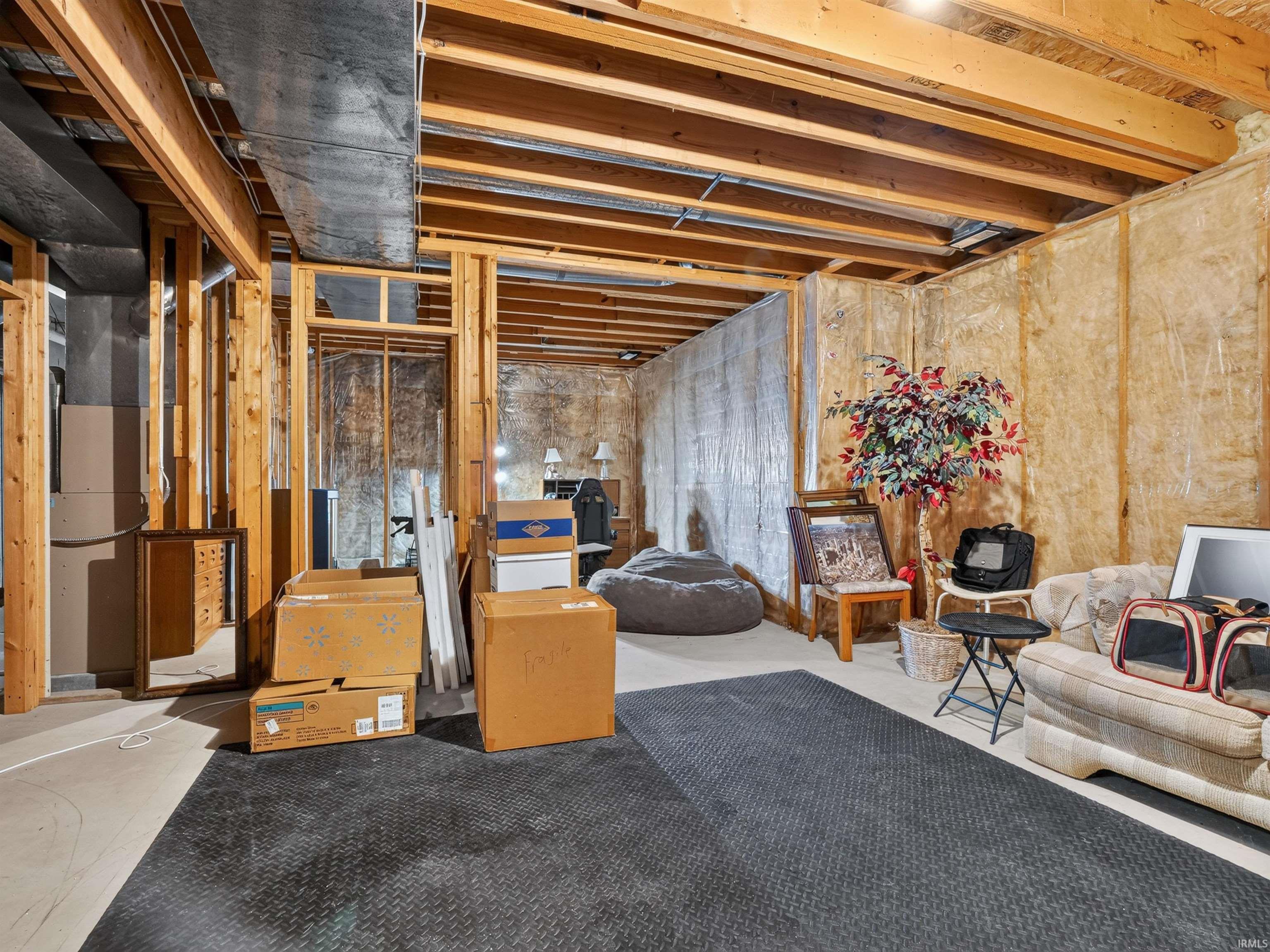 Unfinished basement with exposed wood framing, visible ceiling joists, and a concrete floor