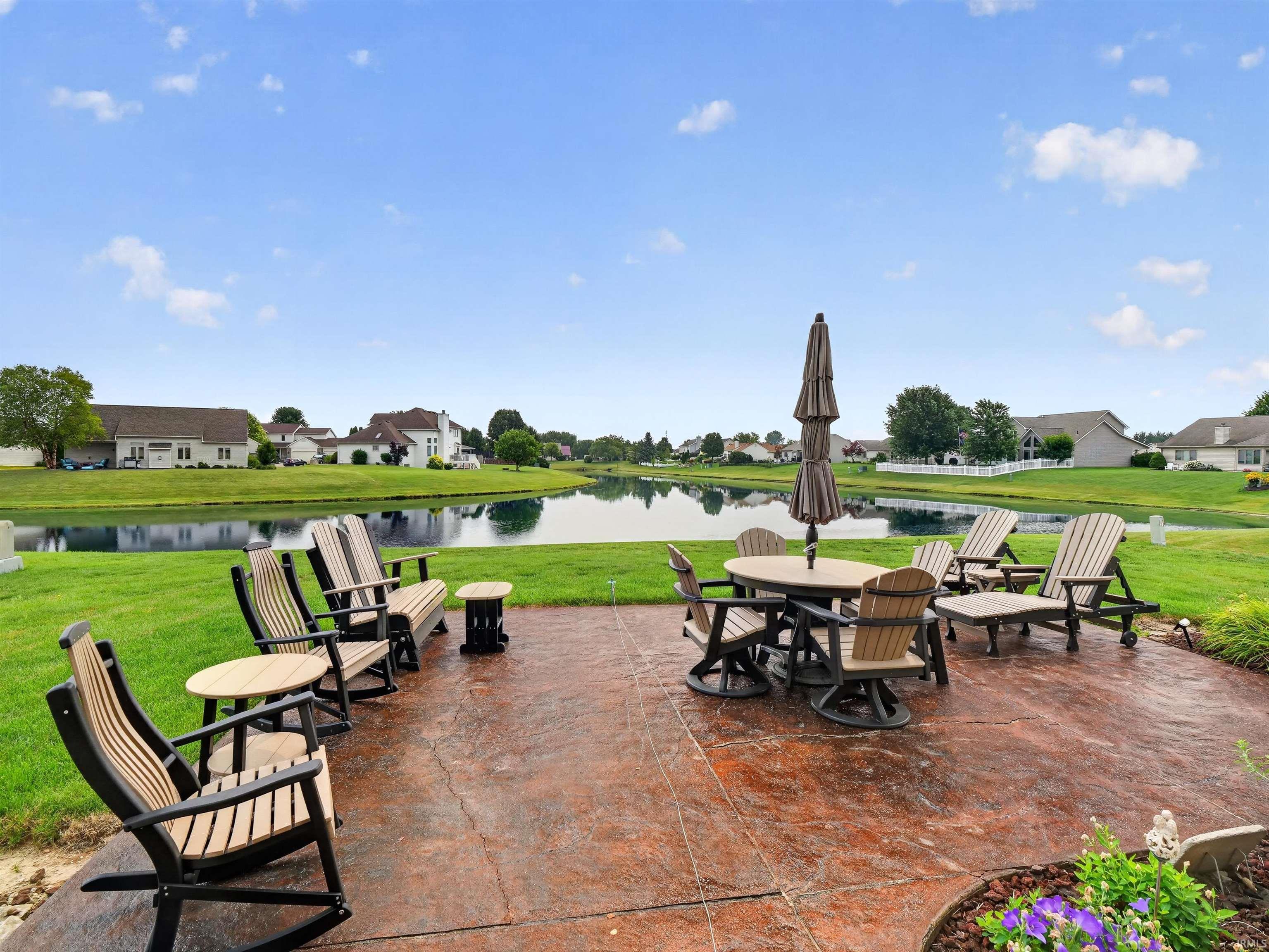Stamped concrete patio with a water feature backdrop, expansive green space, and landscape planting