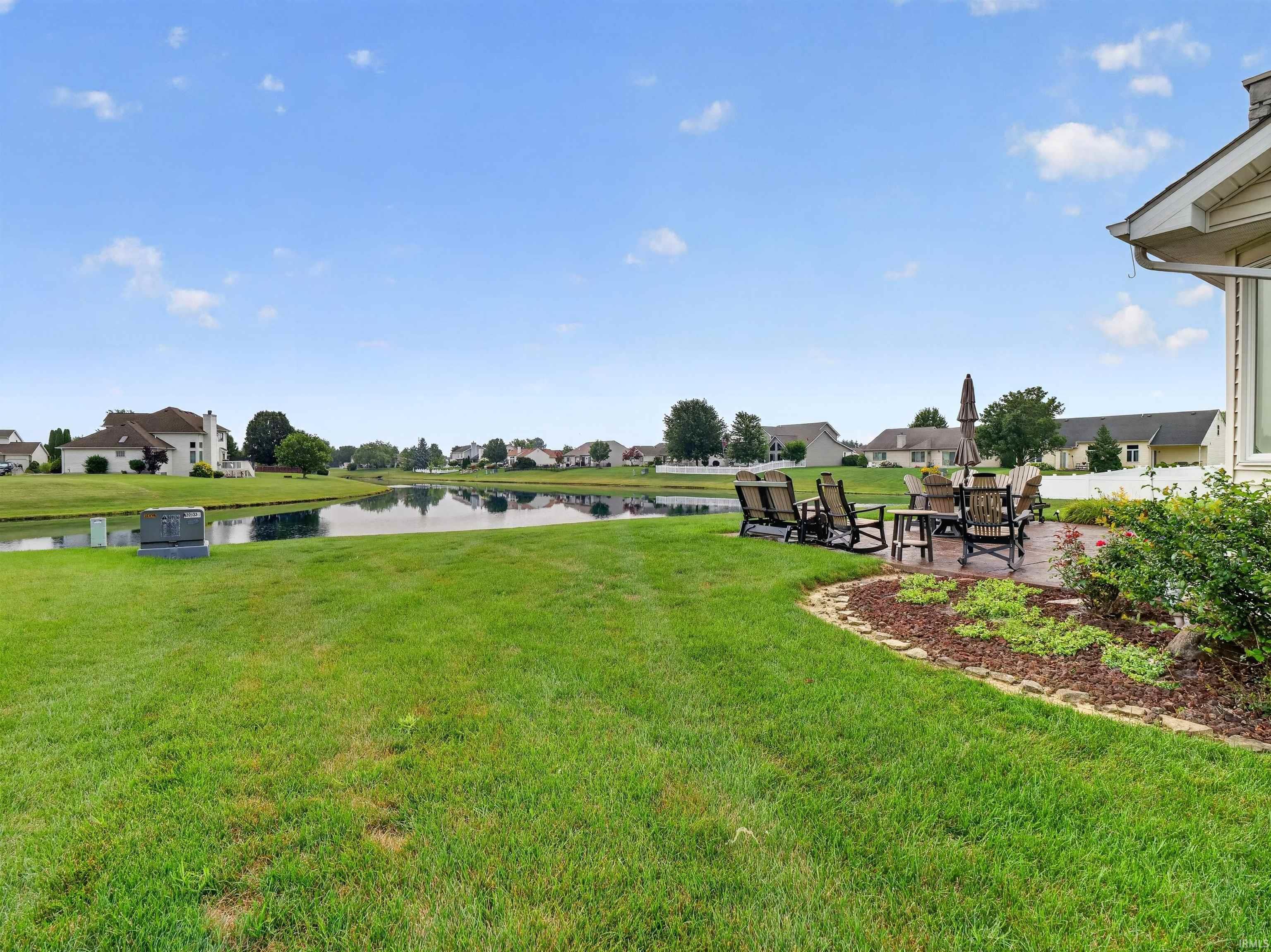 Expansive green lawn with a curved stone patio featuring an outdoor dining area