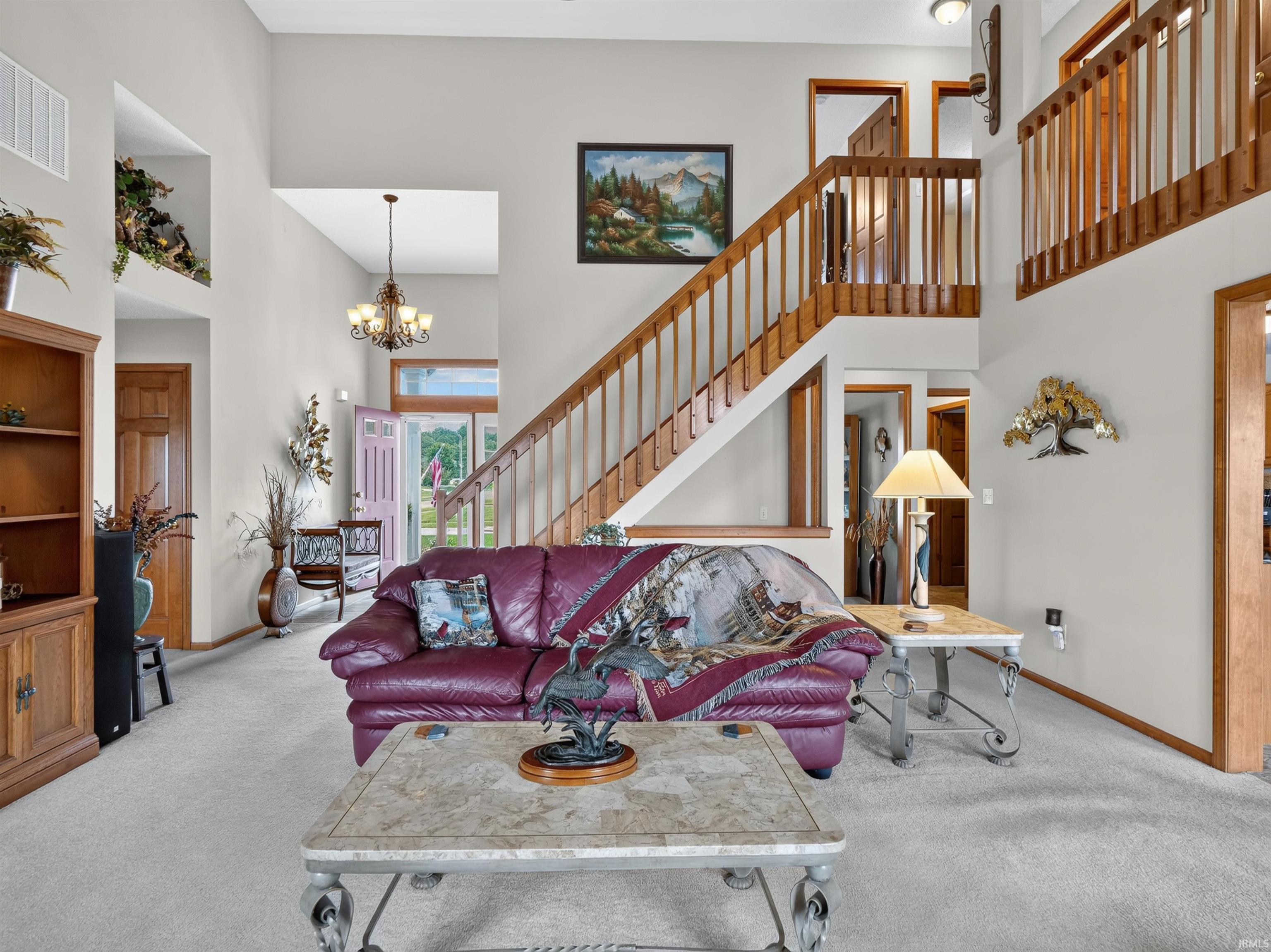 Two-story entry foyer with staircase featuring wood balusters, high ceilings, and a second-story overlook