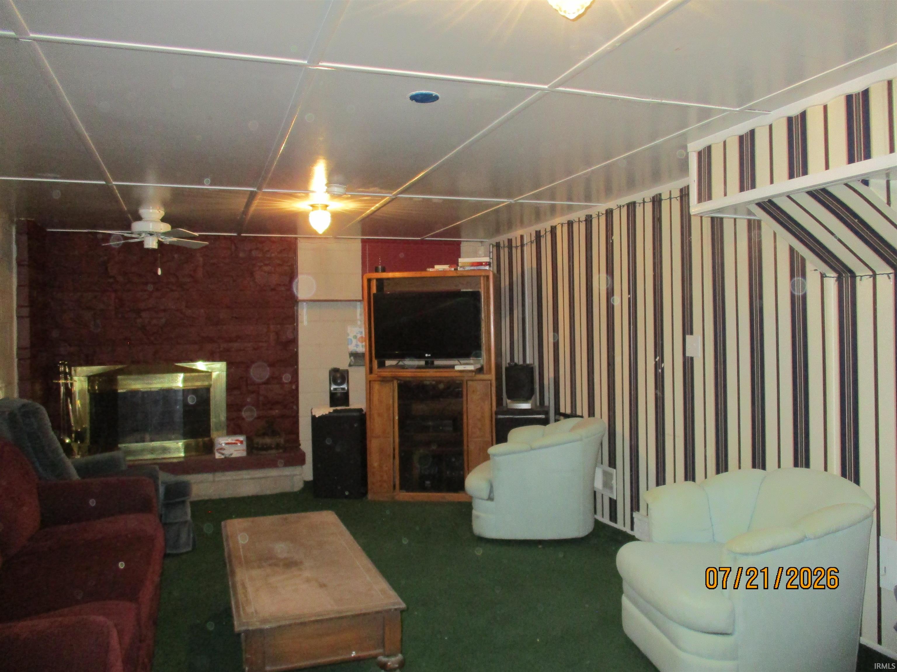 Recreation room featuring a red brick fireplace with a brass firebox surround and a light-colored hearth