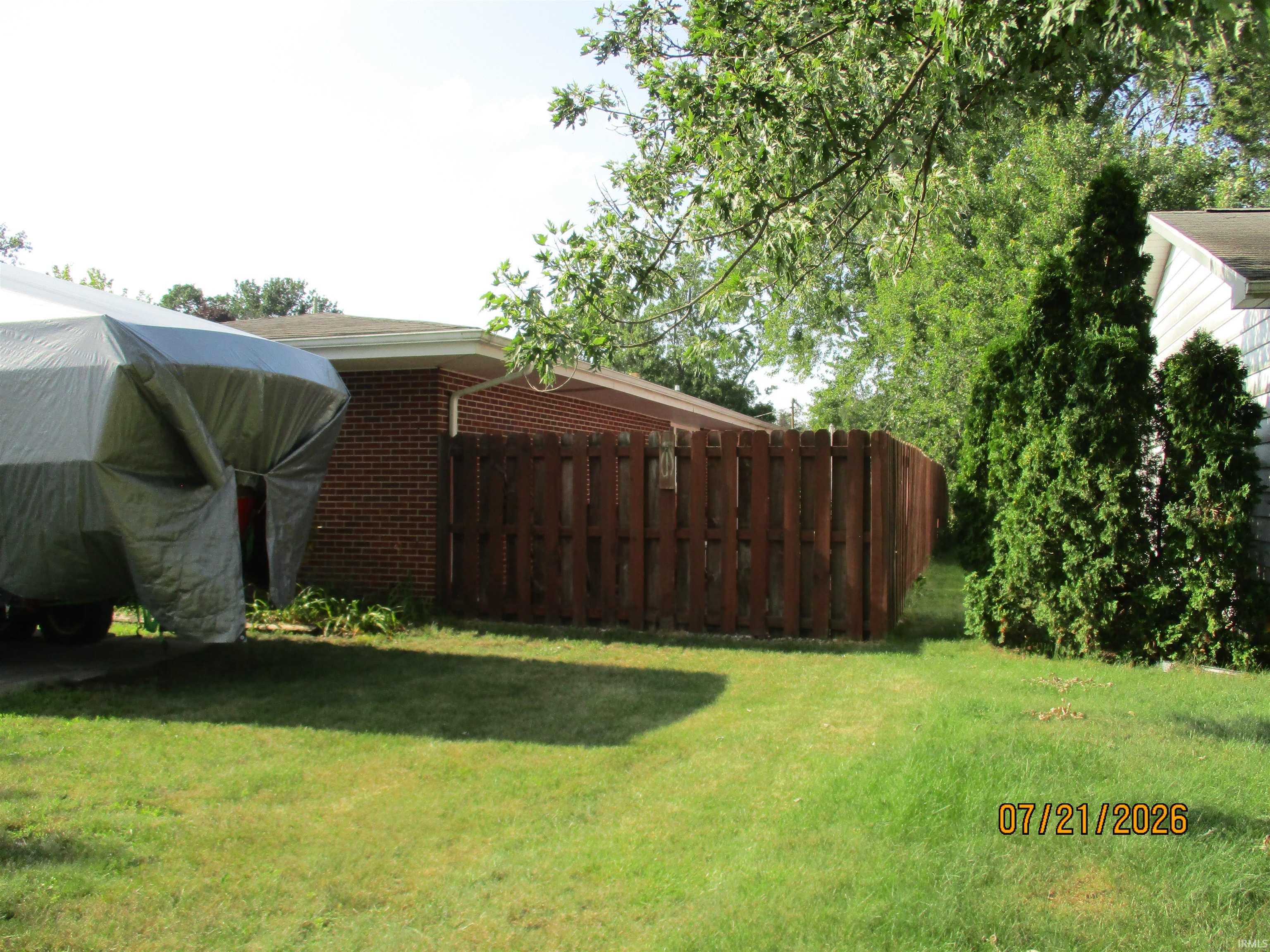 Expansive lawn area featuring a wood privacy fence and mature trees