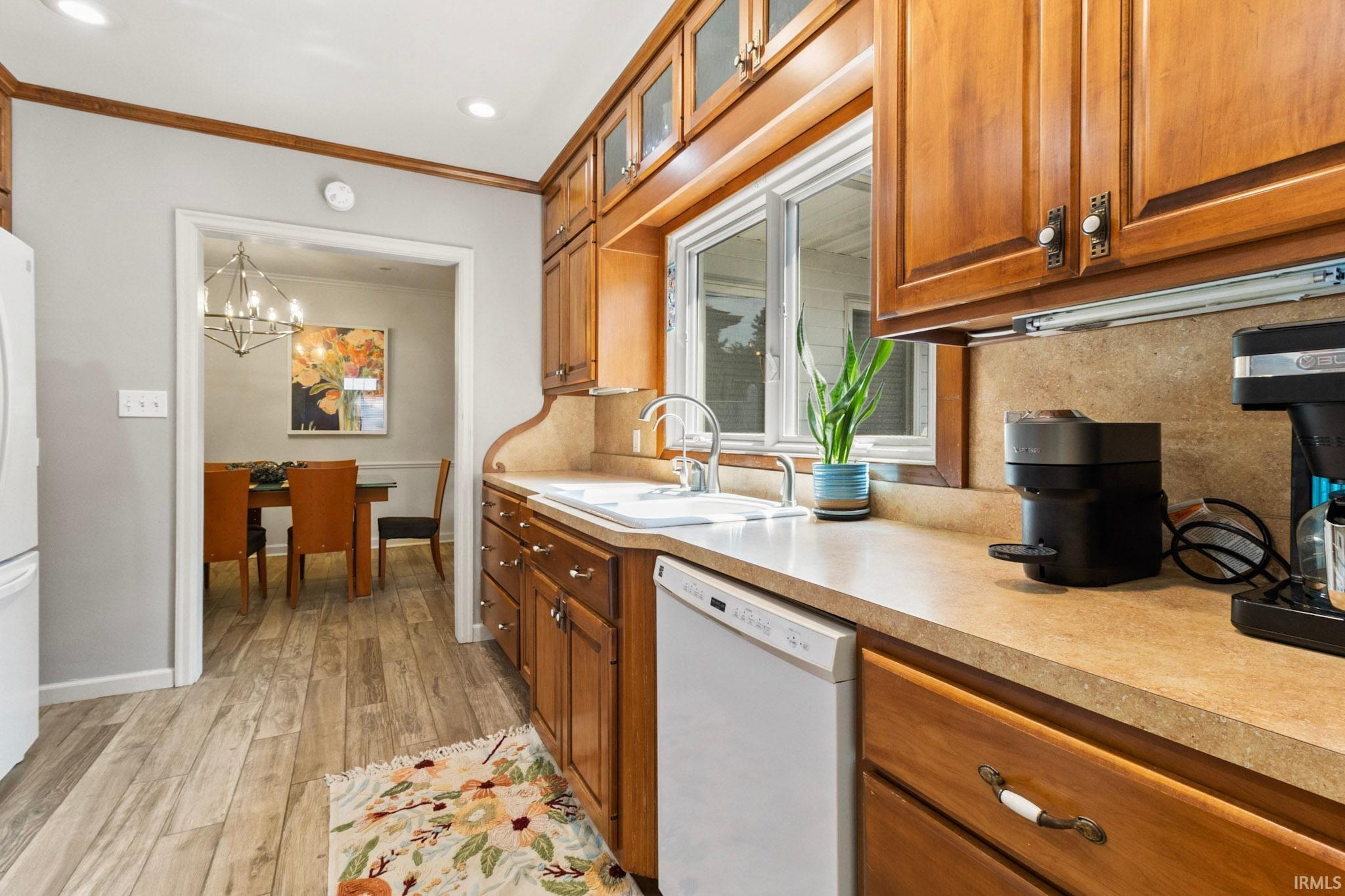 Kitchen featuring wood cabinetry, light-toned countertops, a stainless steel faucet, and a window above the sink