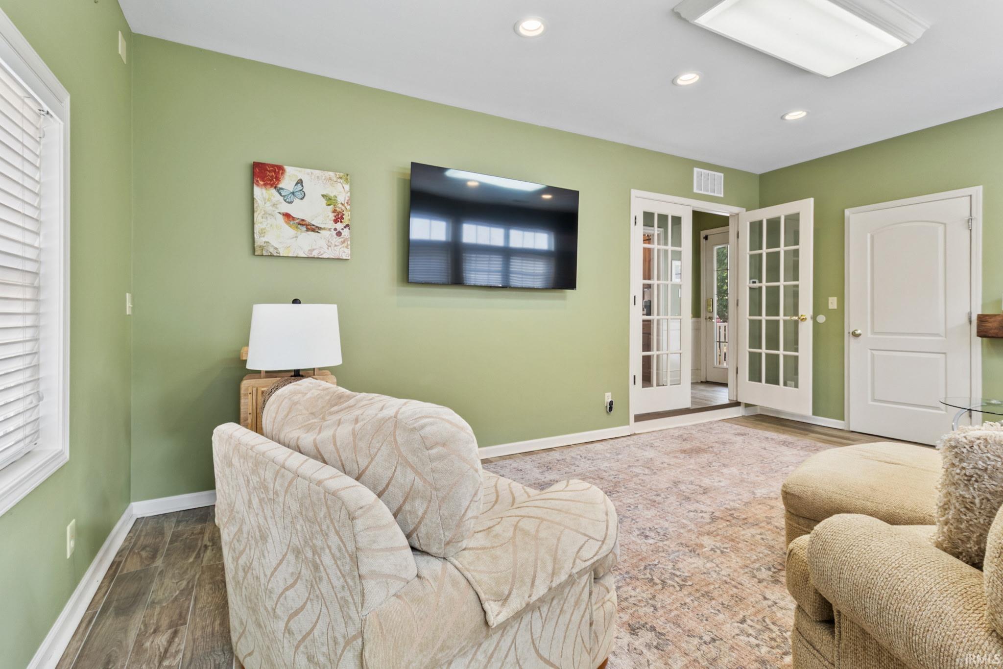 Living area featuring wood-finish flooring, recessed lighting, and a large central rug
