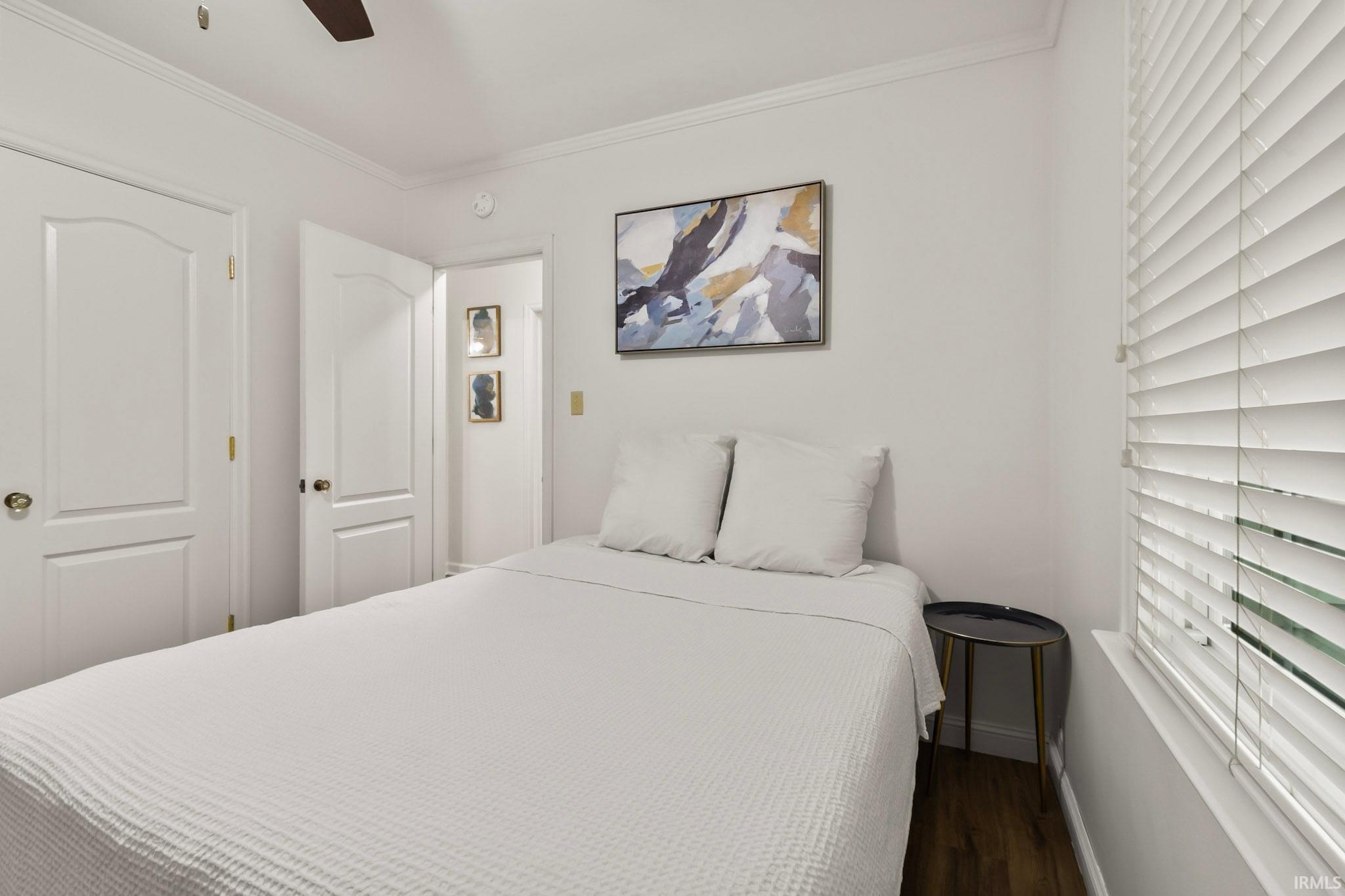 Room featuring wood-finish flooring, white walls, and a ceiling fan