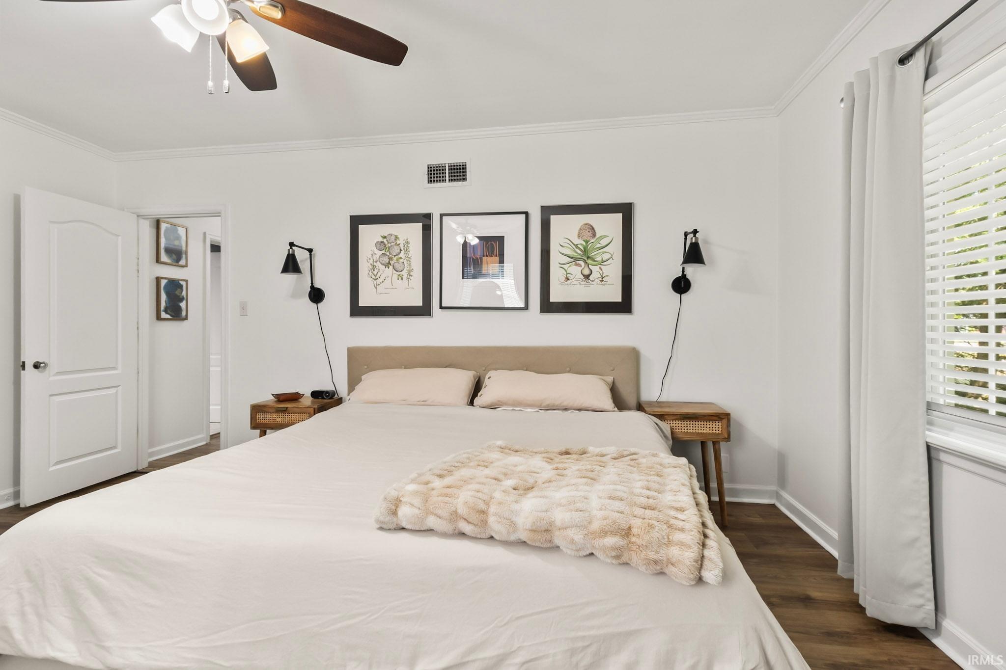 Bedroom featuring wood-finish flooring, a ceiling fan with integrated lighting, crown molding, and a window with blinds