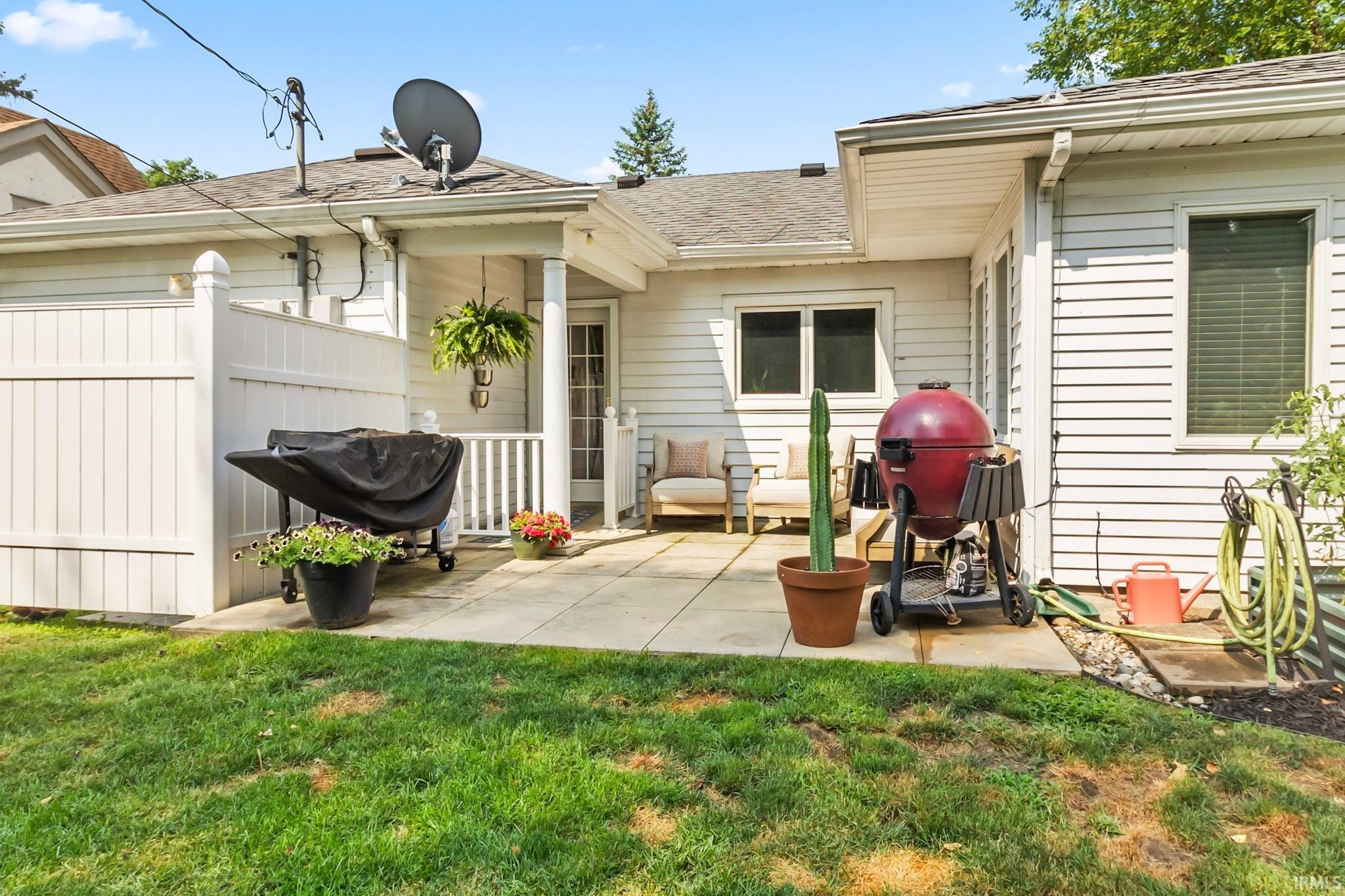 Backyard patio featuring a white vinyl privacy fence, concrete paver flooring, and white siding