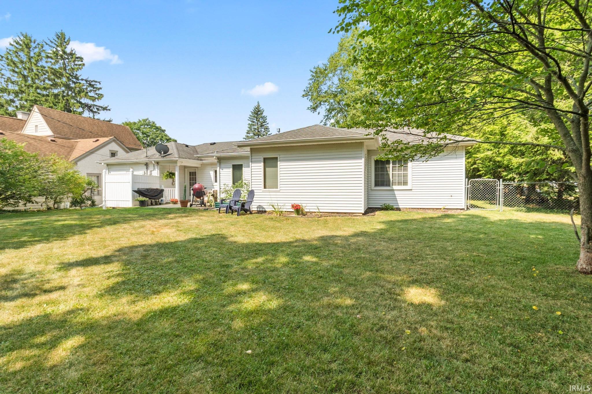 Expansive lawn area with mature trees and a chain-link fence