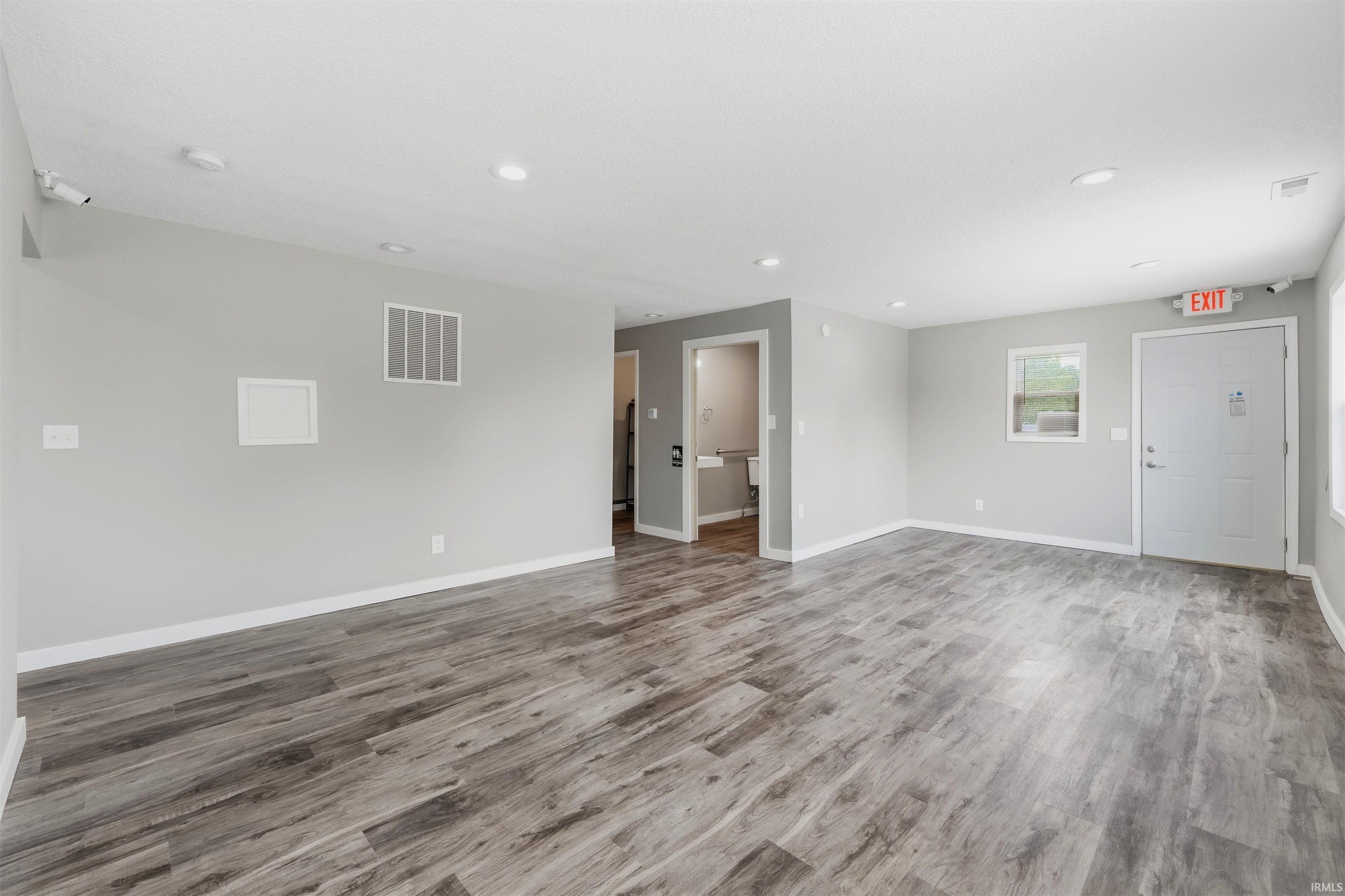 Spacious interior featuring wood-finish flooring, light grey painted walls, and recessed ceiling lighting