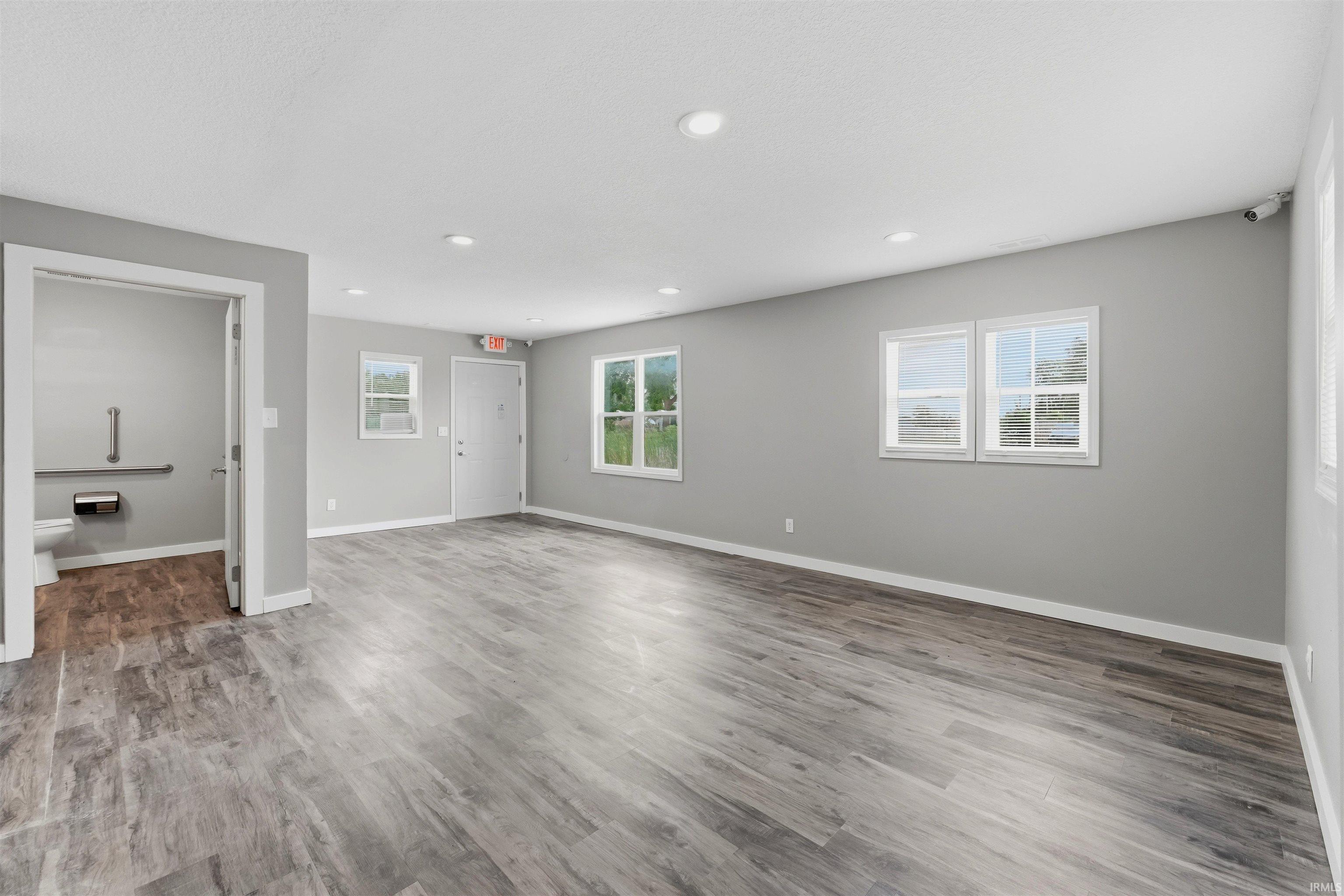 Spacious room featuring wood-finish flooring, recessed lighting, and multiple windows