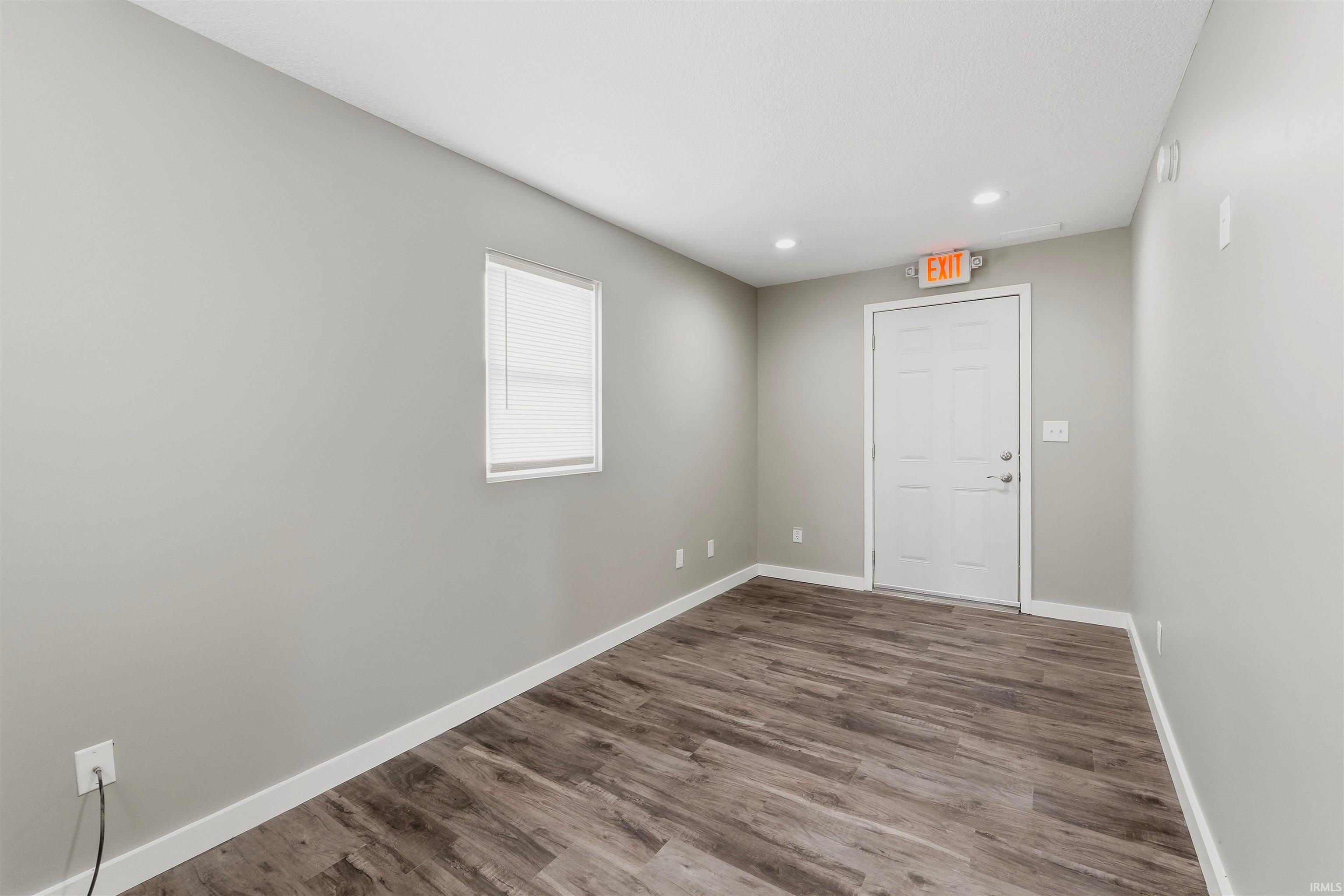Room featuring wood-finish flooring, recessed lighting, and a window with blinds