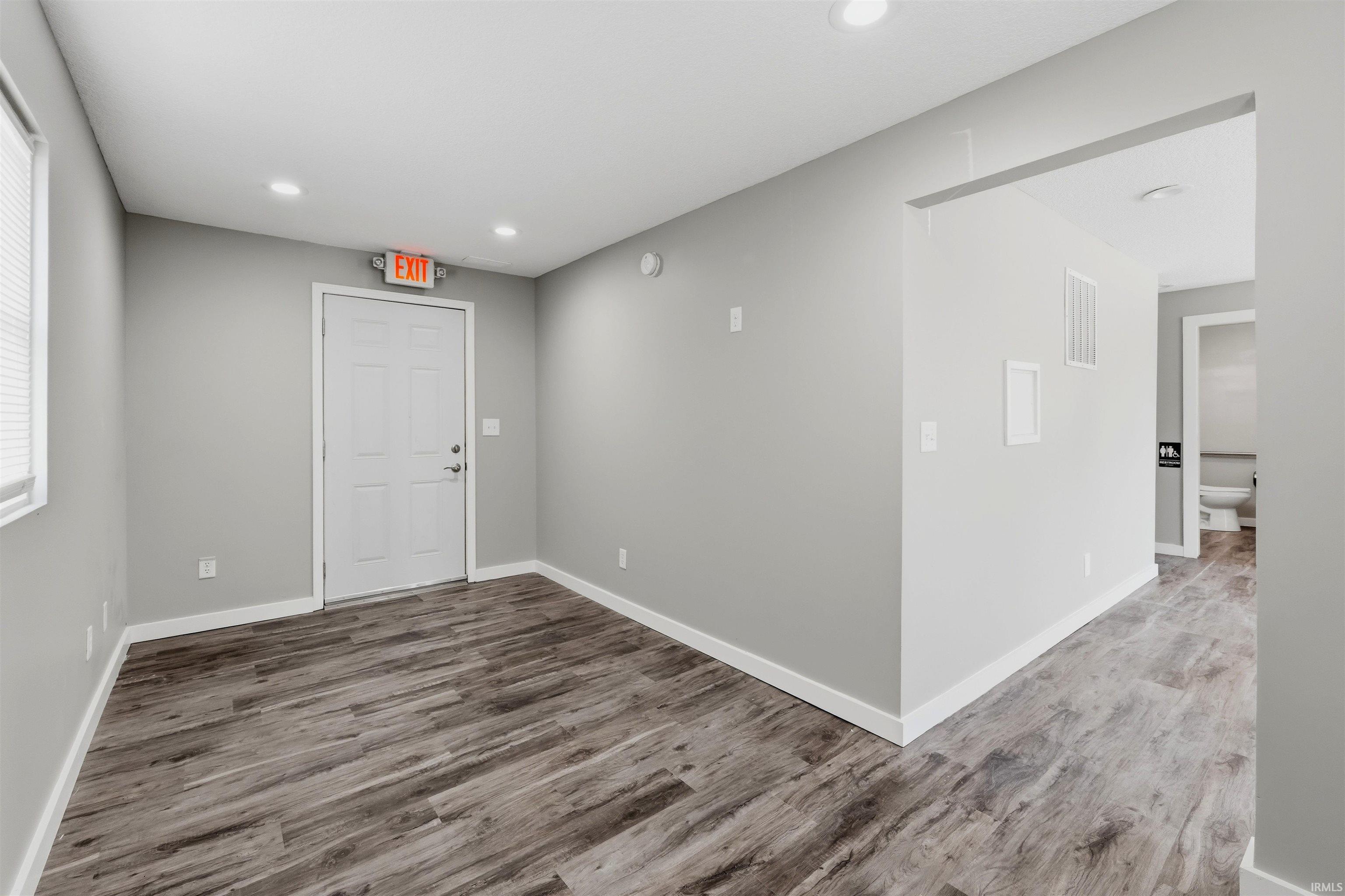 Spacious room featuring wood-finish flooring, light grey walls, and recessed lighting
