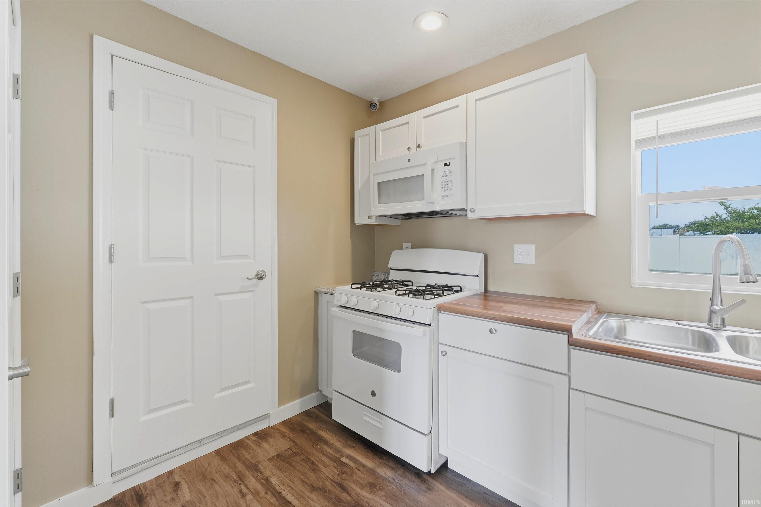 Kitchen featuring white shaker-style cabinetry, wood-finish countertops, and wood-finish flooring