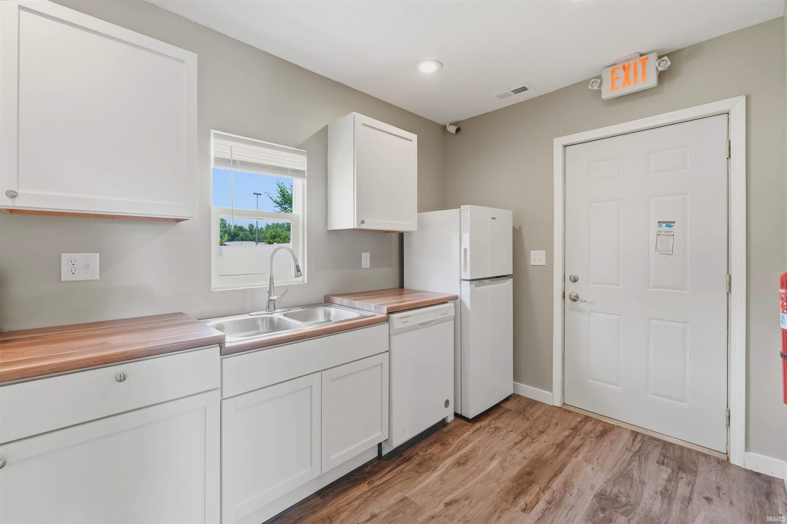 Kitchenette featuring wood-finish countertops, white cabinetry, and wood-finish flooring