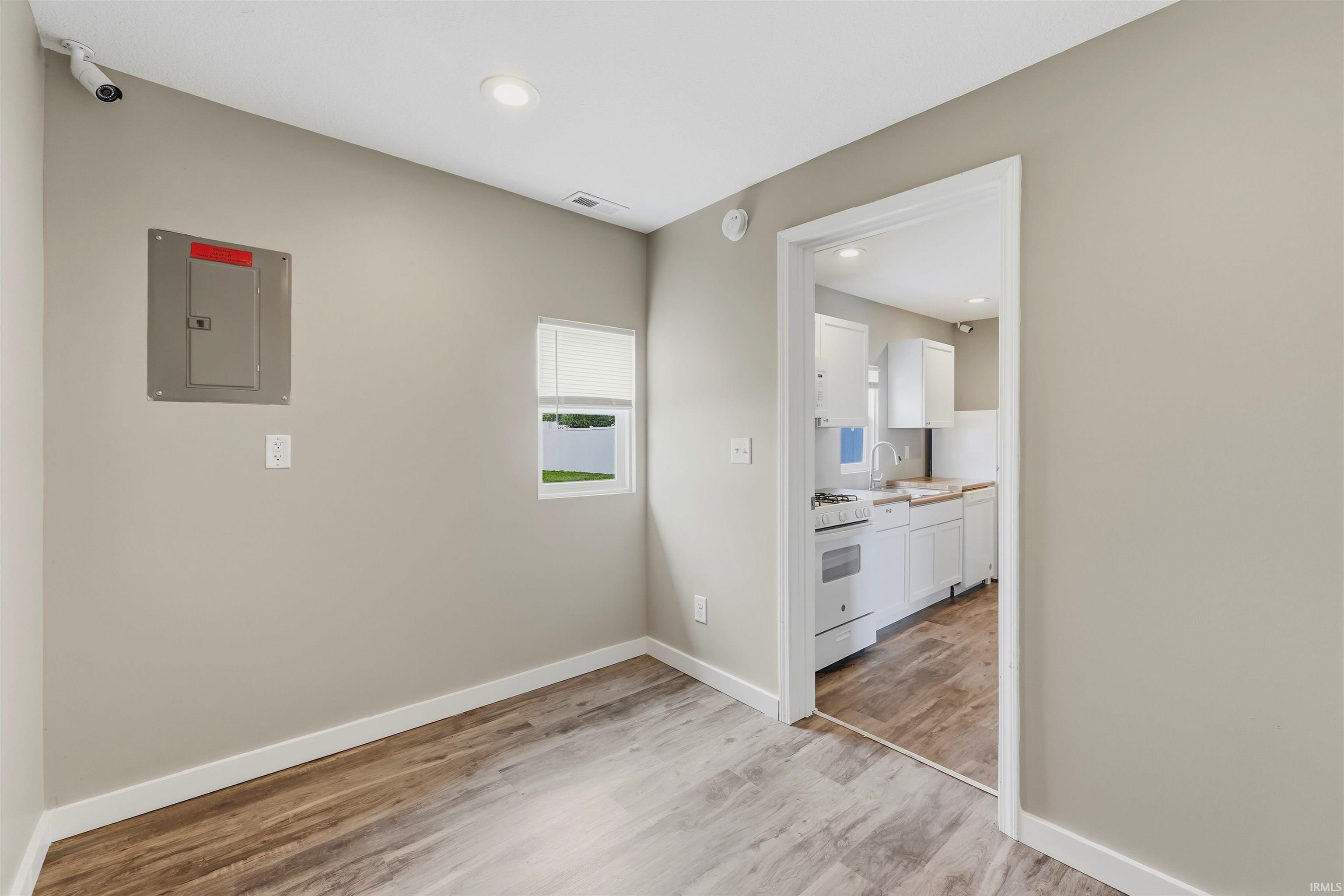 Room with wood-finish flooring, light-toned walls, and white trim