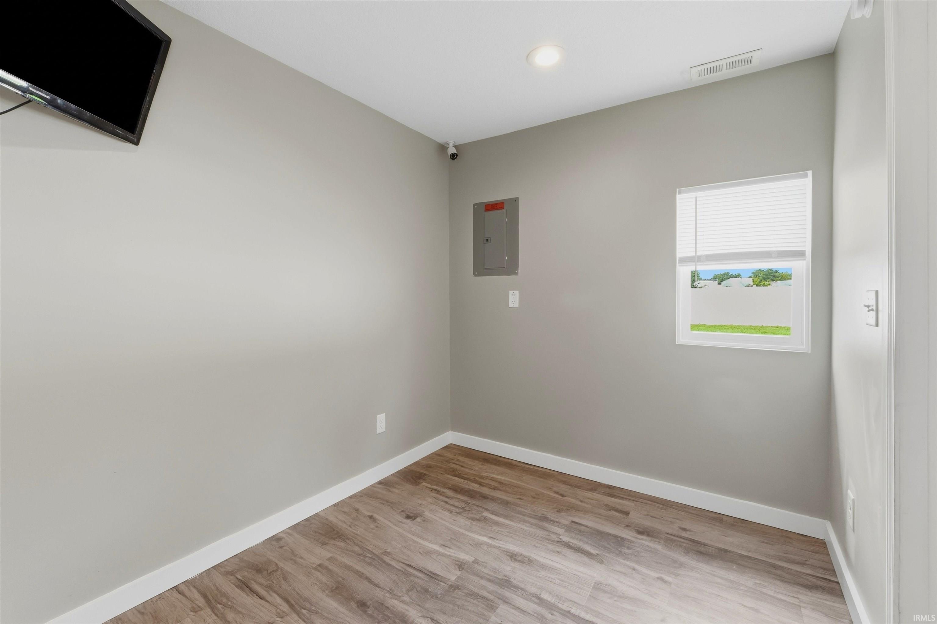 Room with wood-finish flooring, light gray walls, and white baseboards