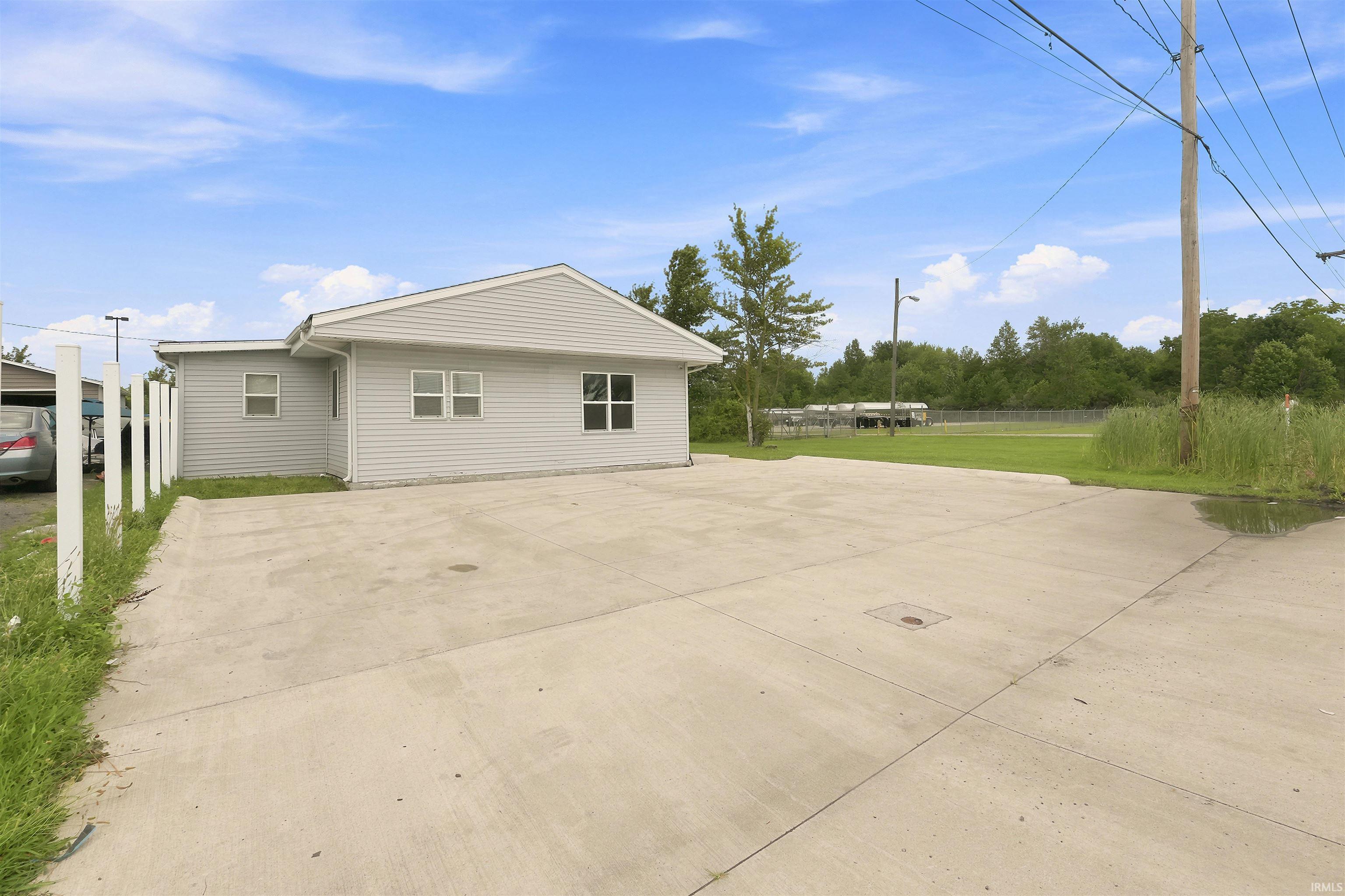 Spacious concrete driveway featuring a light-colored exterior with horizontal siding and multiple windows
