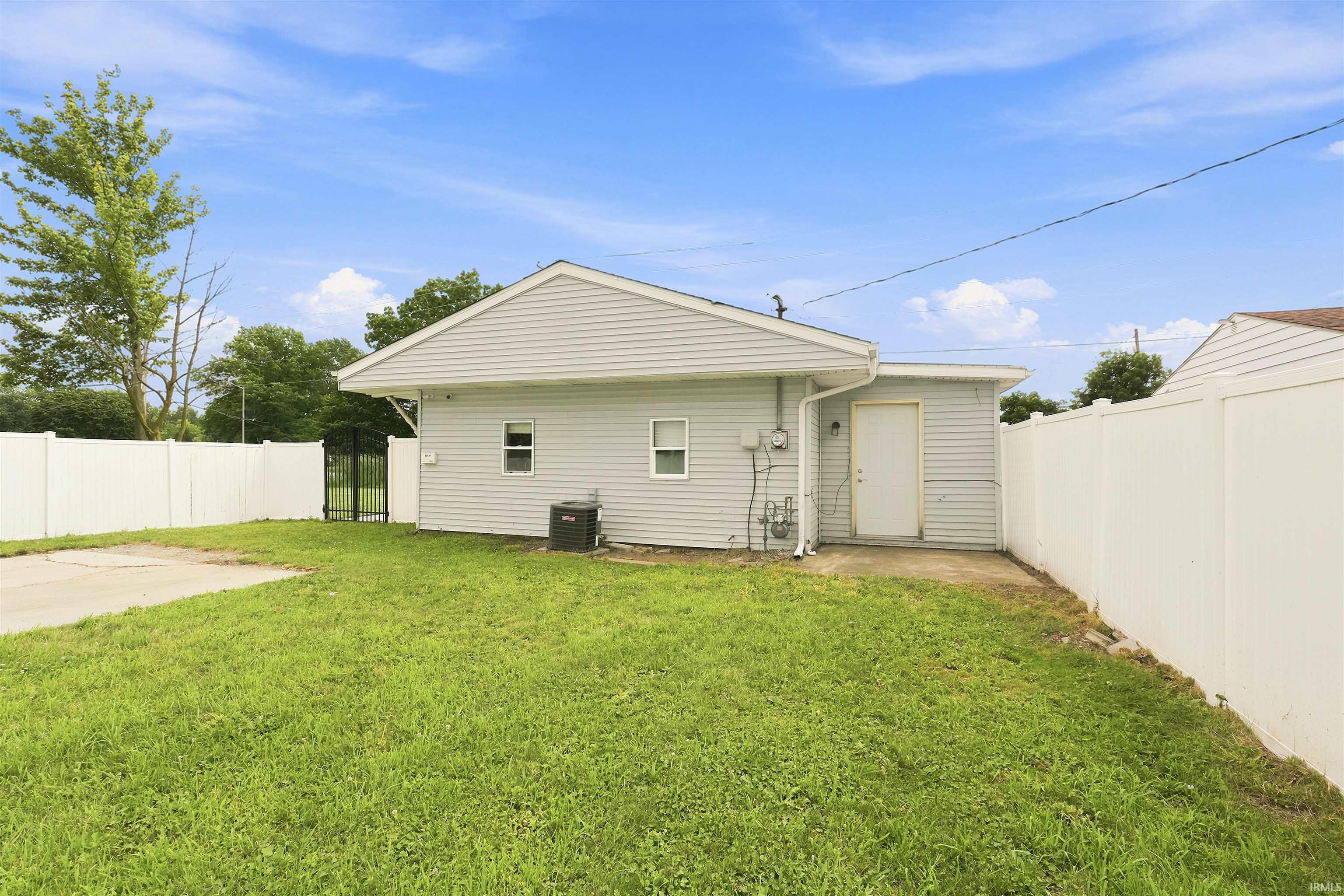 Rear exterior featuring light grey siding and a white privacy fence enclosing the backyard