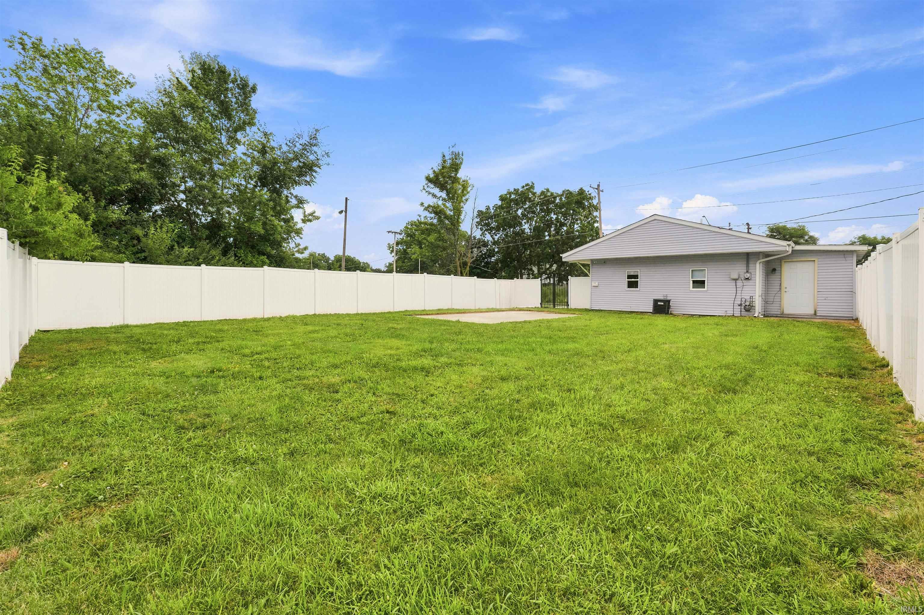 Expansive green lawn framed by a white vinyl privacy fence