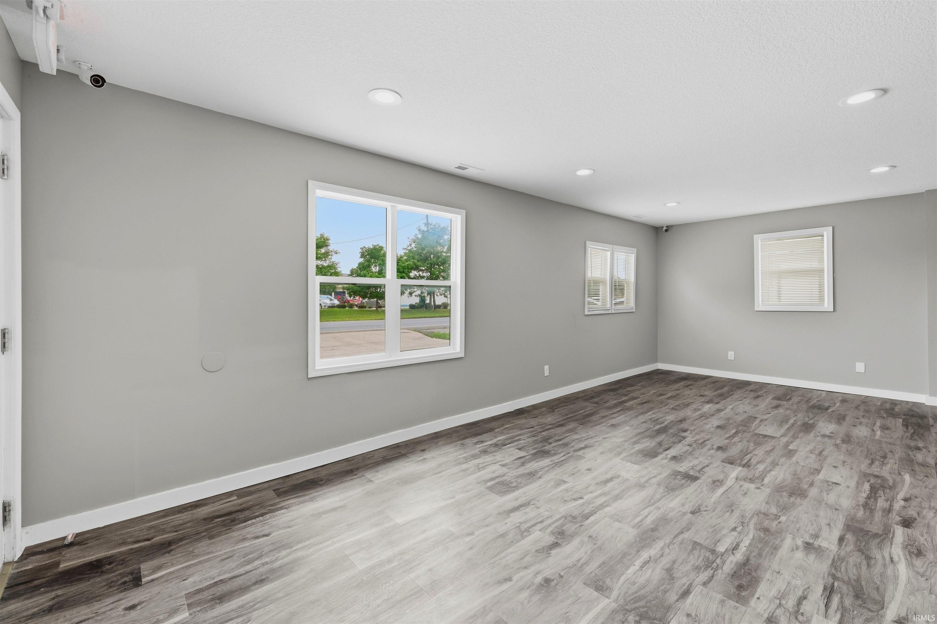 Spacious room featuring wood-finish flooring, light gray walls, white trim, and recessed lighting