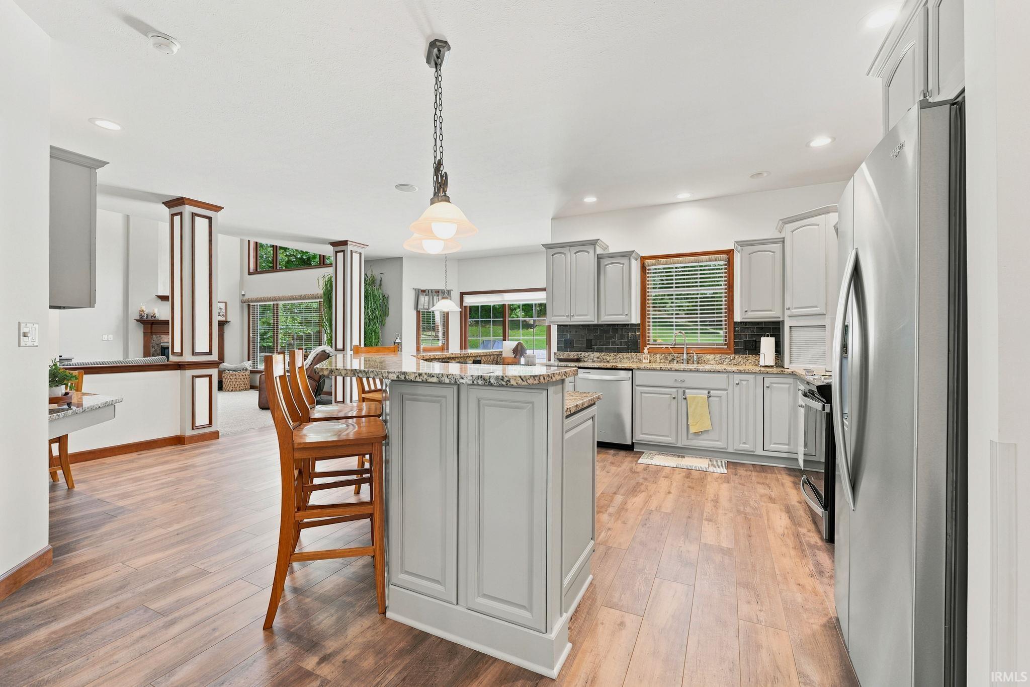Kitchen featuring a center island, light gray cabinetry, stainless steel appliances, granite countertops, and wood-finish flooring