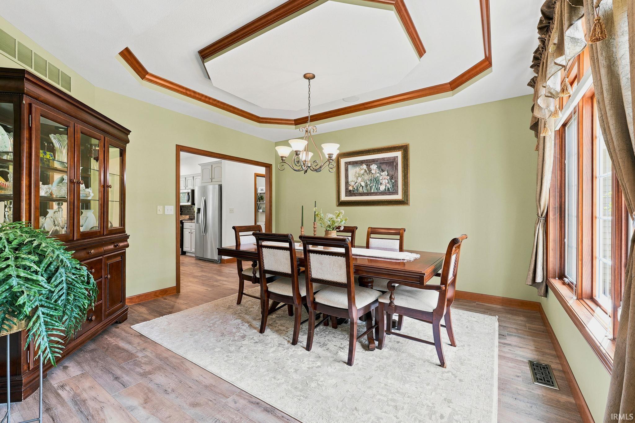 Dining area featuring wood-finish flooring, a tray ceiling with wood trim, and a multi-pane window with wood-frame construction