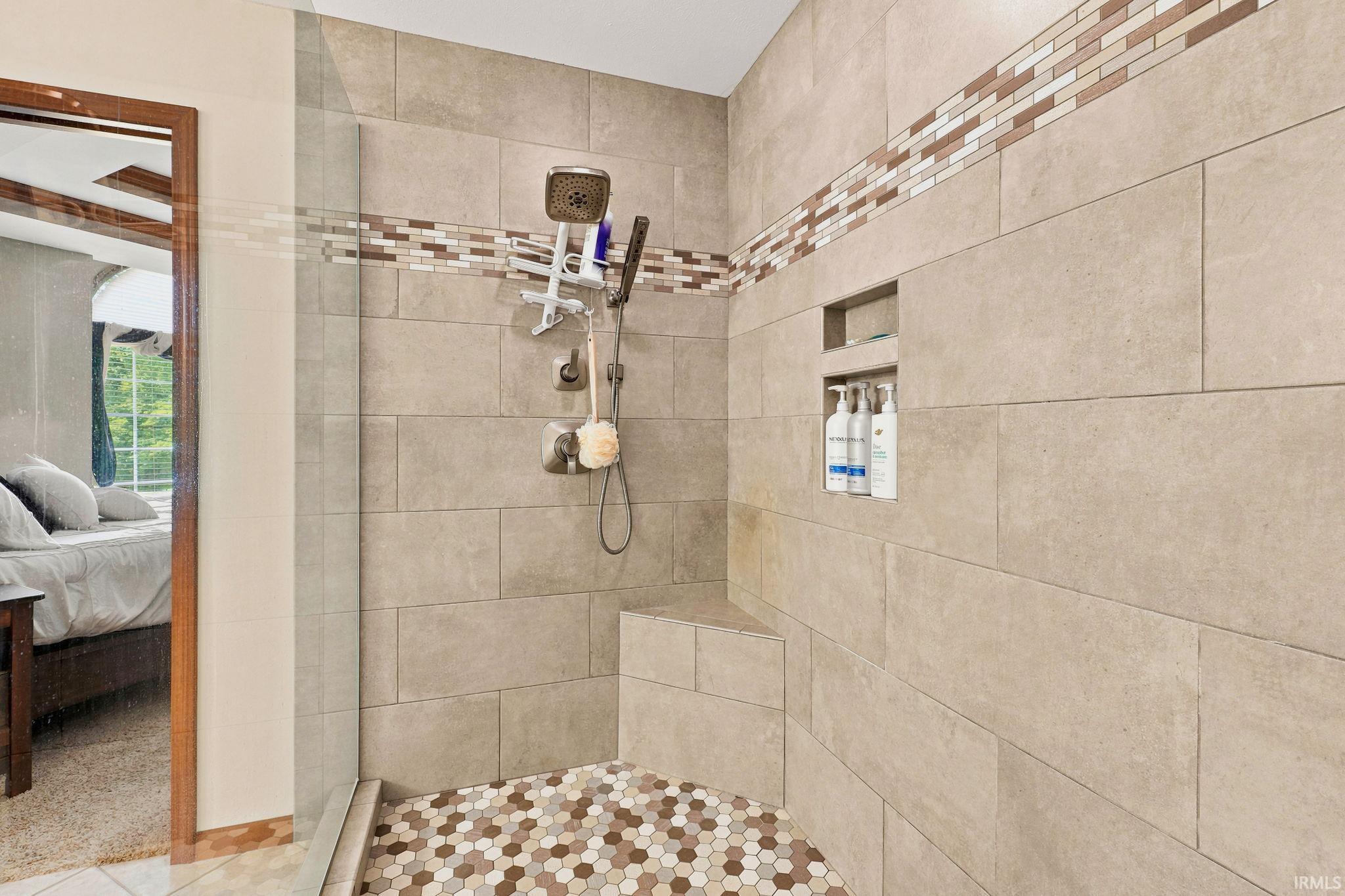 Tiled shower enclosure featuring a multi-function shower head, built-in bench, and recessed shelving