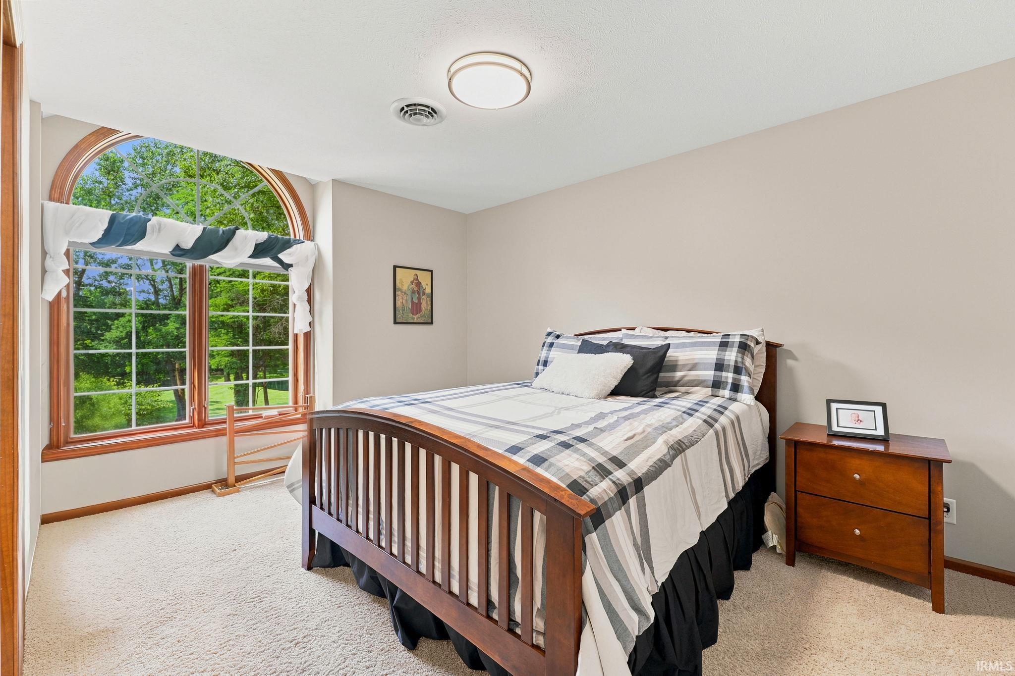 Arched window featuring wood trim, multiple window panes, and a verdant outdoor landscape