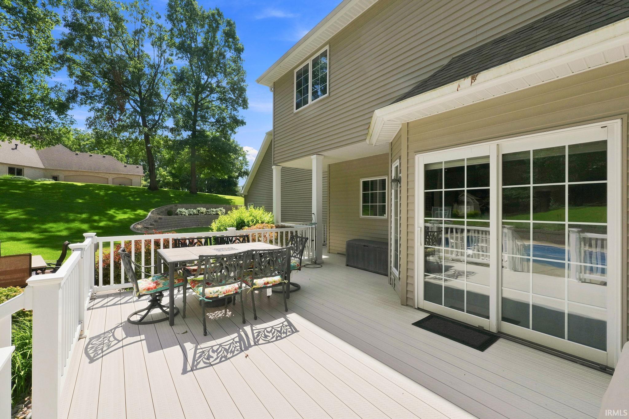 Spacious outdoor deck with white railing, featuring sliding glass doors and light-colored siding