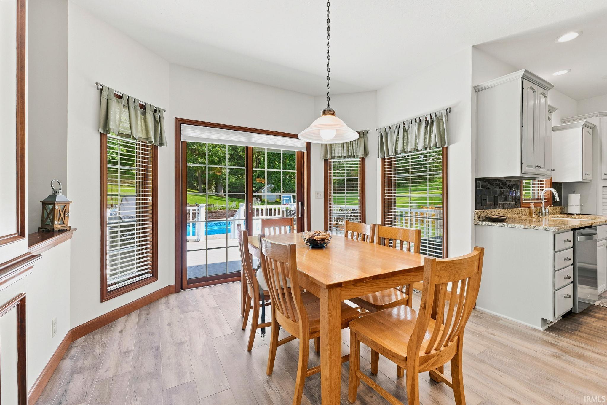 Dining area featuring wood-finish flooring, a glass sliding door, and multiple windows with wood trim