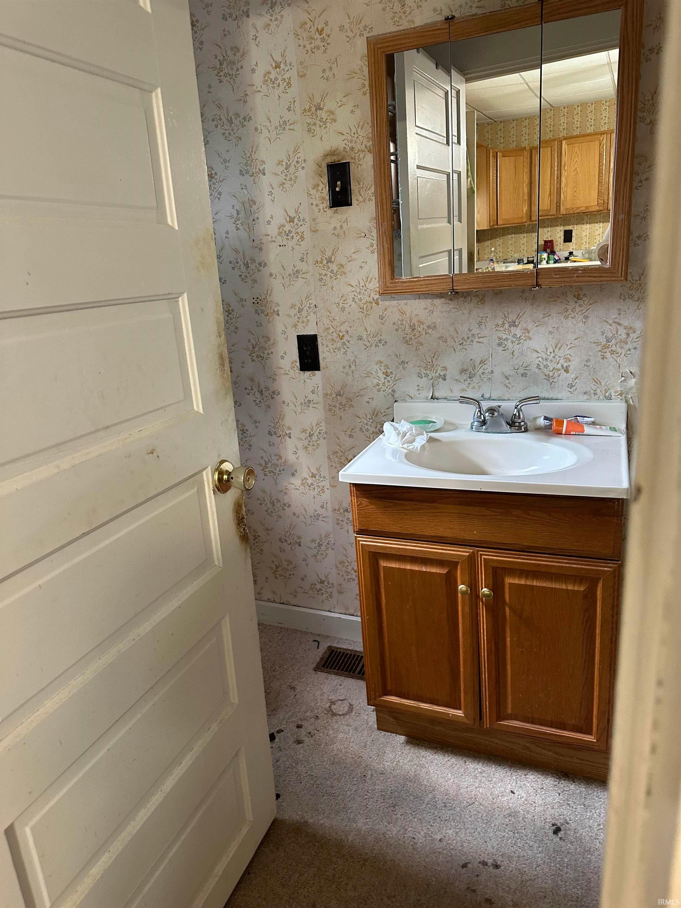 Wood-finish vanity cabinetry with a white integrated sink, paired with a framed wall mirror