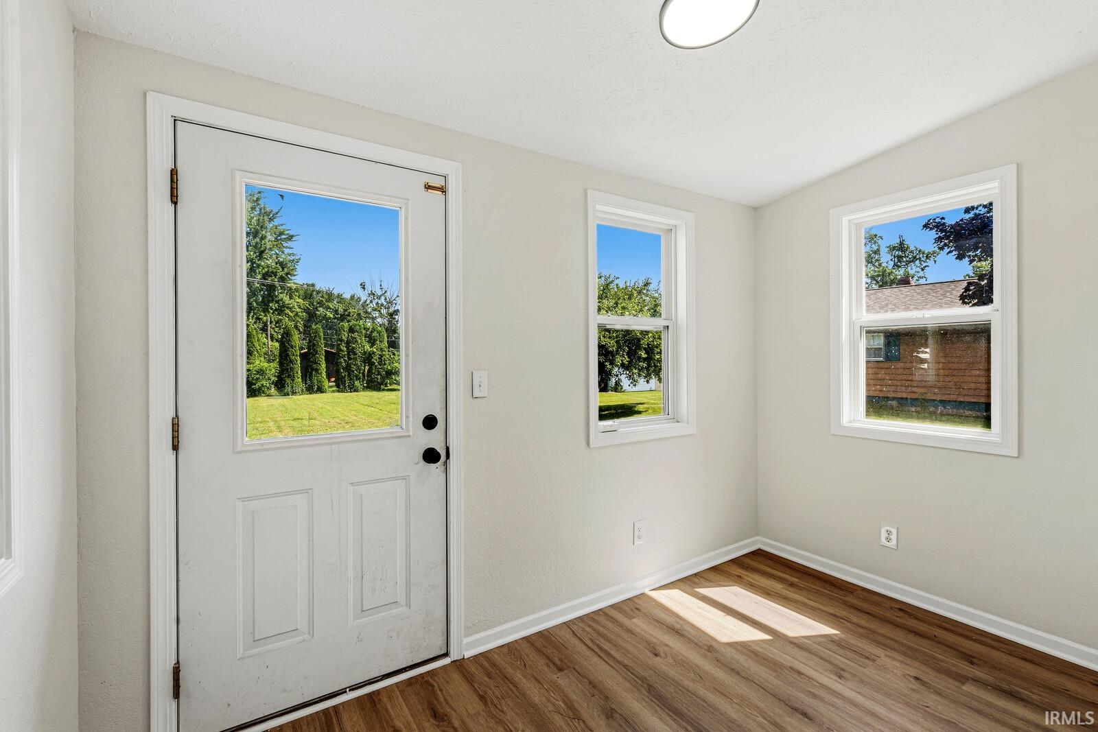 Room with wood-finish flooring, light neutral wall paint, and white trim