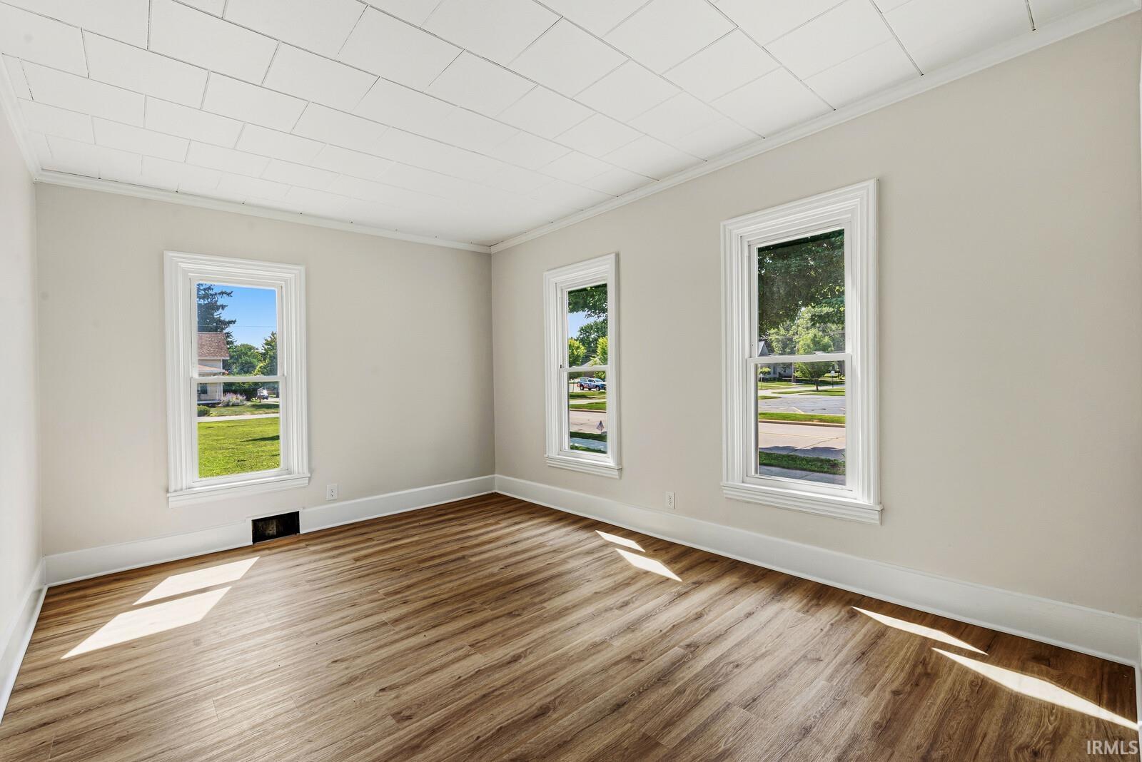 Spacious room featuring wood-finish flooring, light neutral wall paint, and white trim