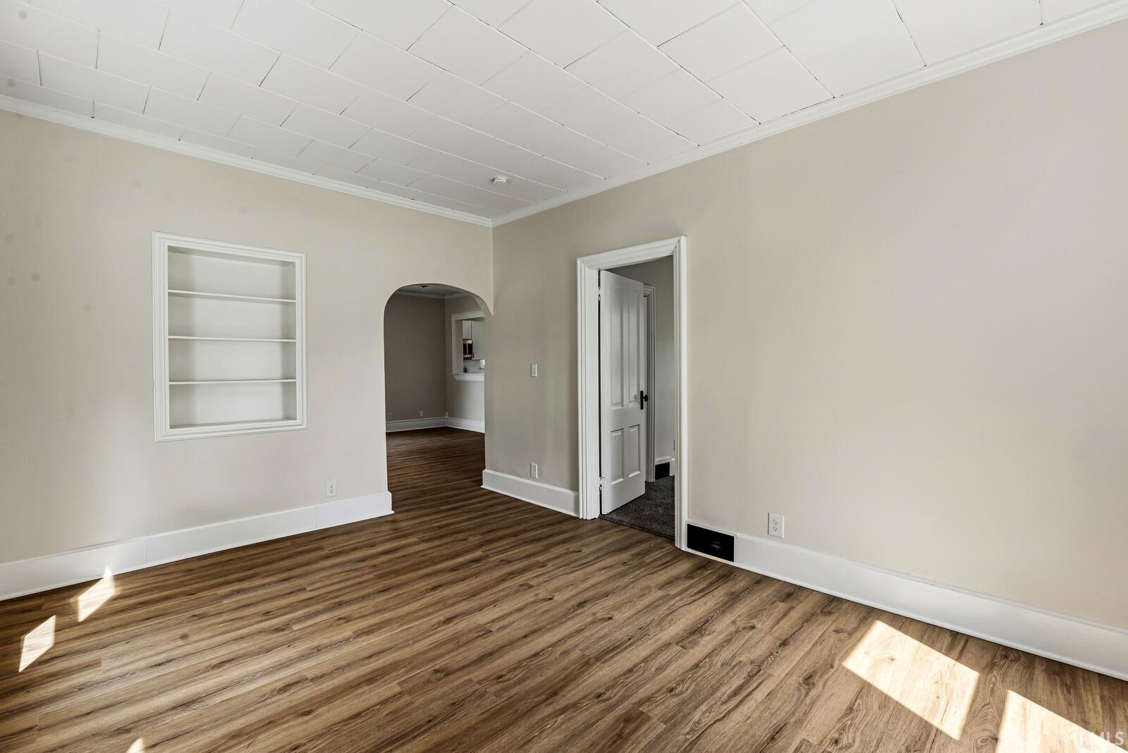 Spacious interior featuring wood-finish flooring, light neutral wall tones, and a built-in recessed shelf