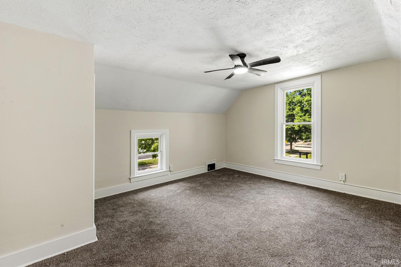 Carpeted room featuring a sloped ceiling and two windows with white trim