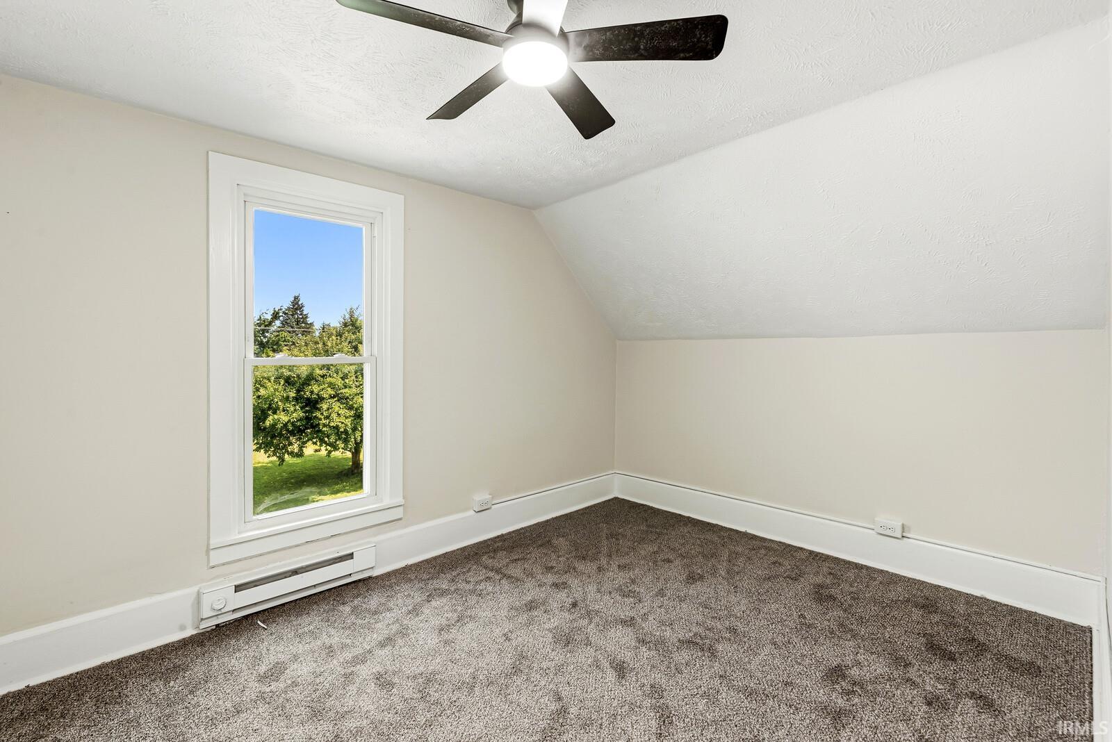 Room with sloped ceilings, light-colored walls, and gray carpeting