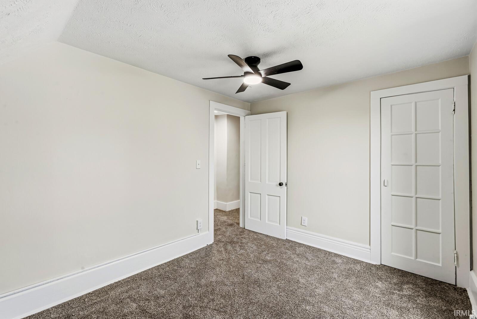 Room featuring neutral-toned walls, textured ceiling, and gray carpet flooring