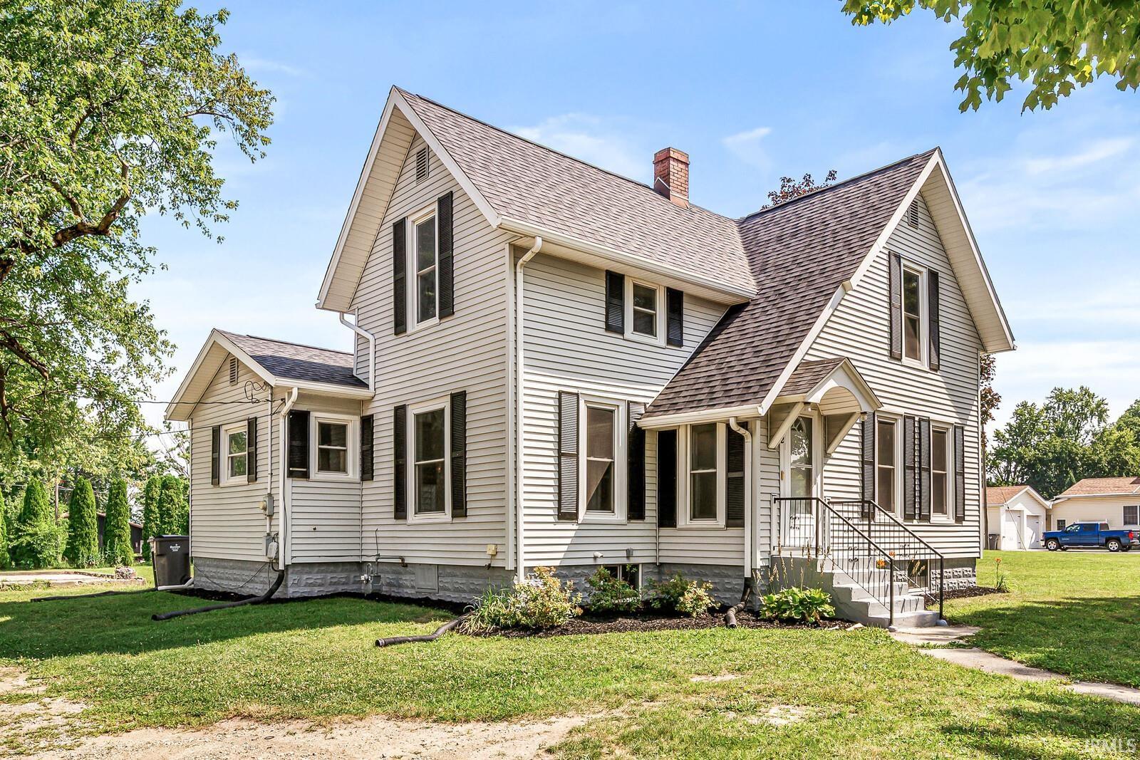 Two-story residence featuring light-colored siding, contrasting dark shutters, and a dark shingle roof