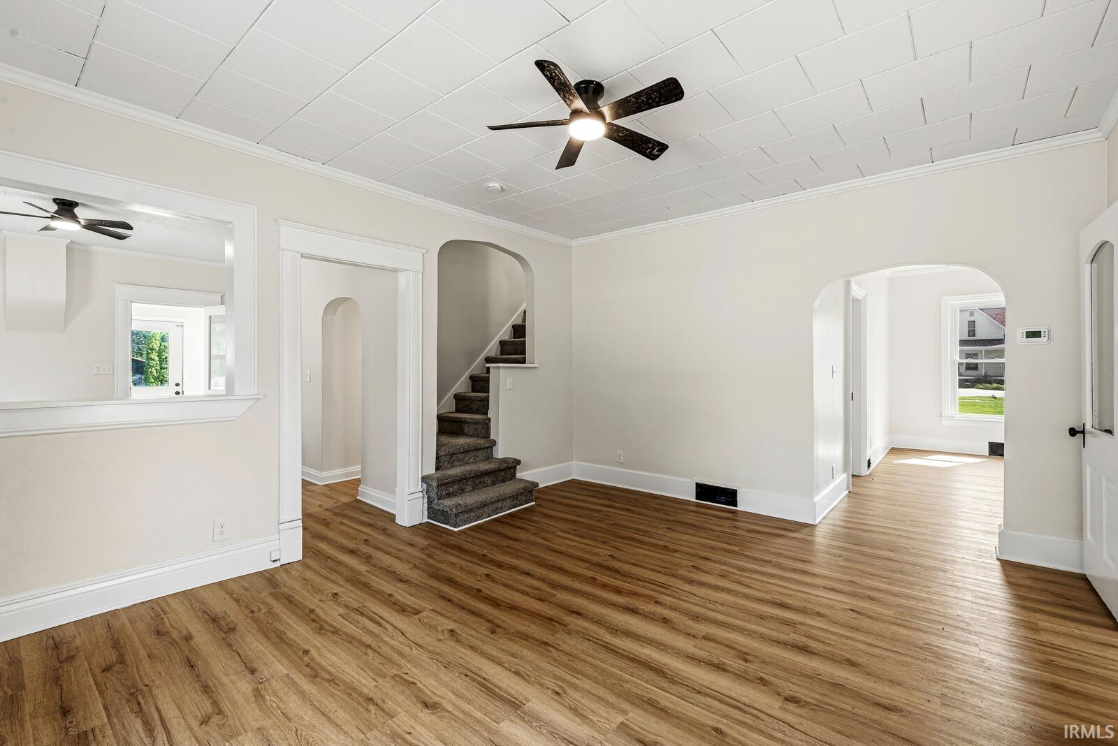 Spacious interior featuring wood-finish flooring, white trim, and a ceiling fan