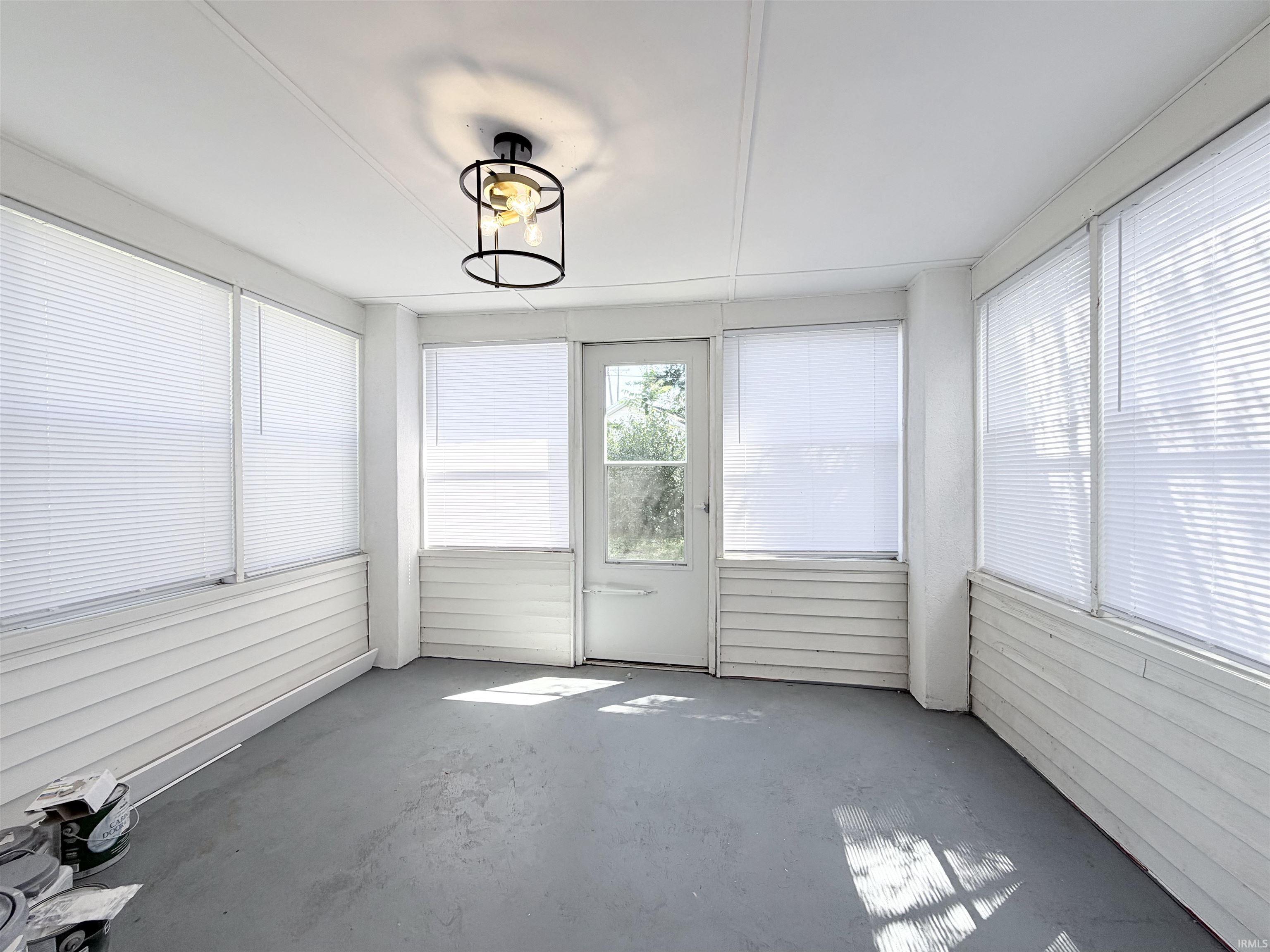 Enclosed porch featuring multiple windows with blinds, a full-light entry door, and a modern semi-flushmount light fixture