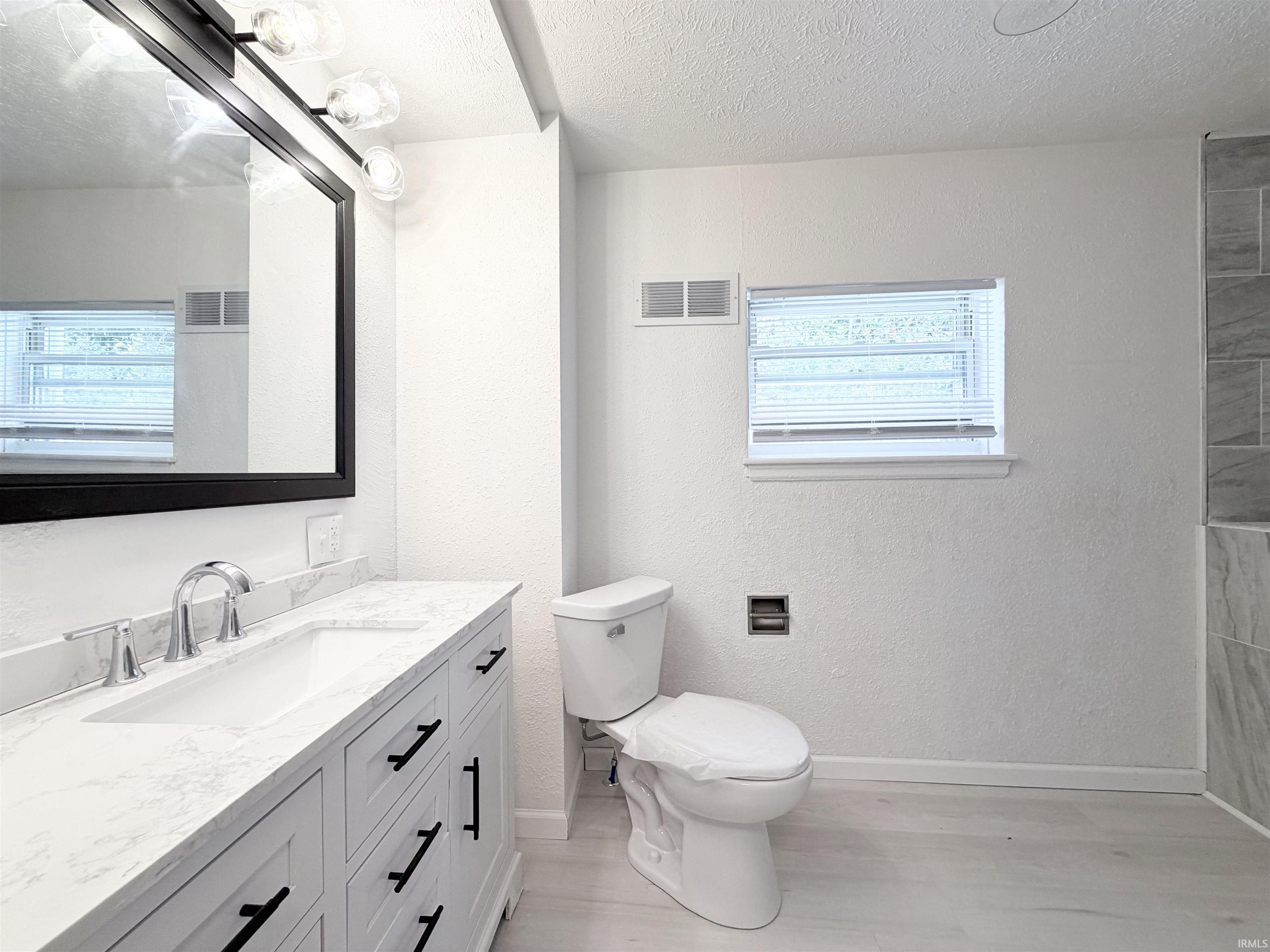 Modern bathroom featuring a single vanity with a white countertop and integrated sink, chrome faucet, and a large black-framed mirror