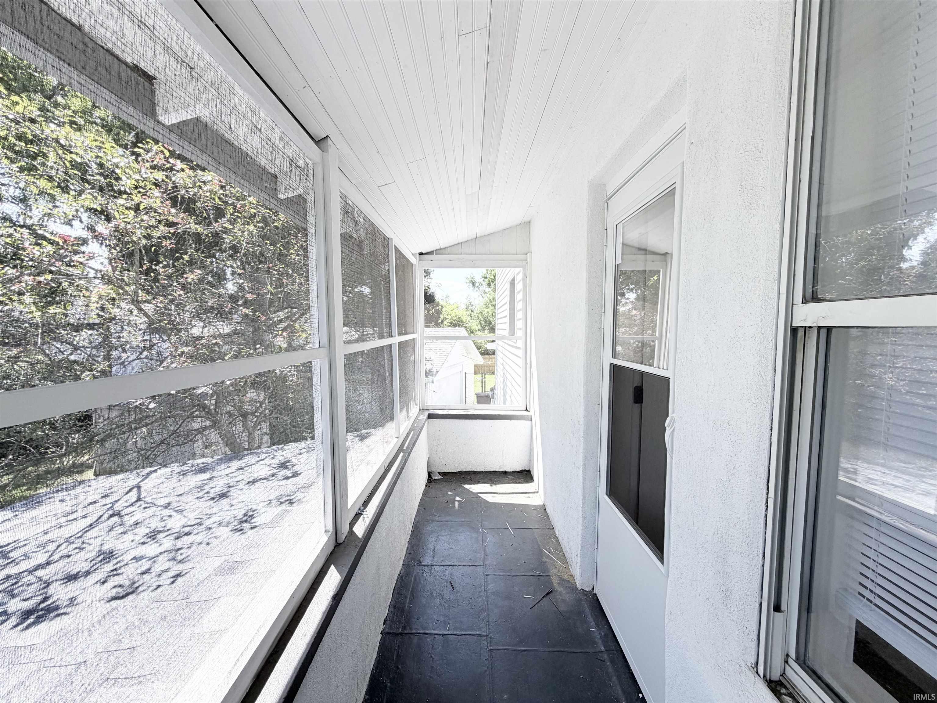 Screened-in porch featuring a planked ceiling, dark tile flooring, and white exterior walls