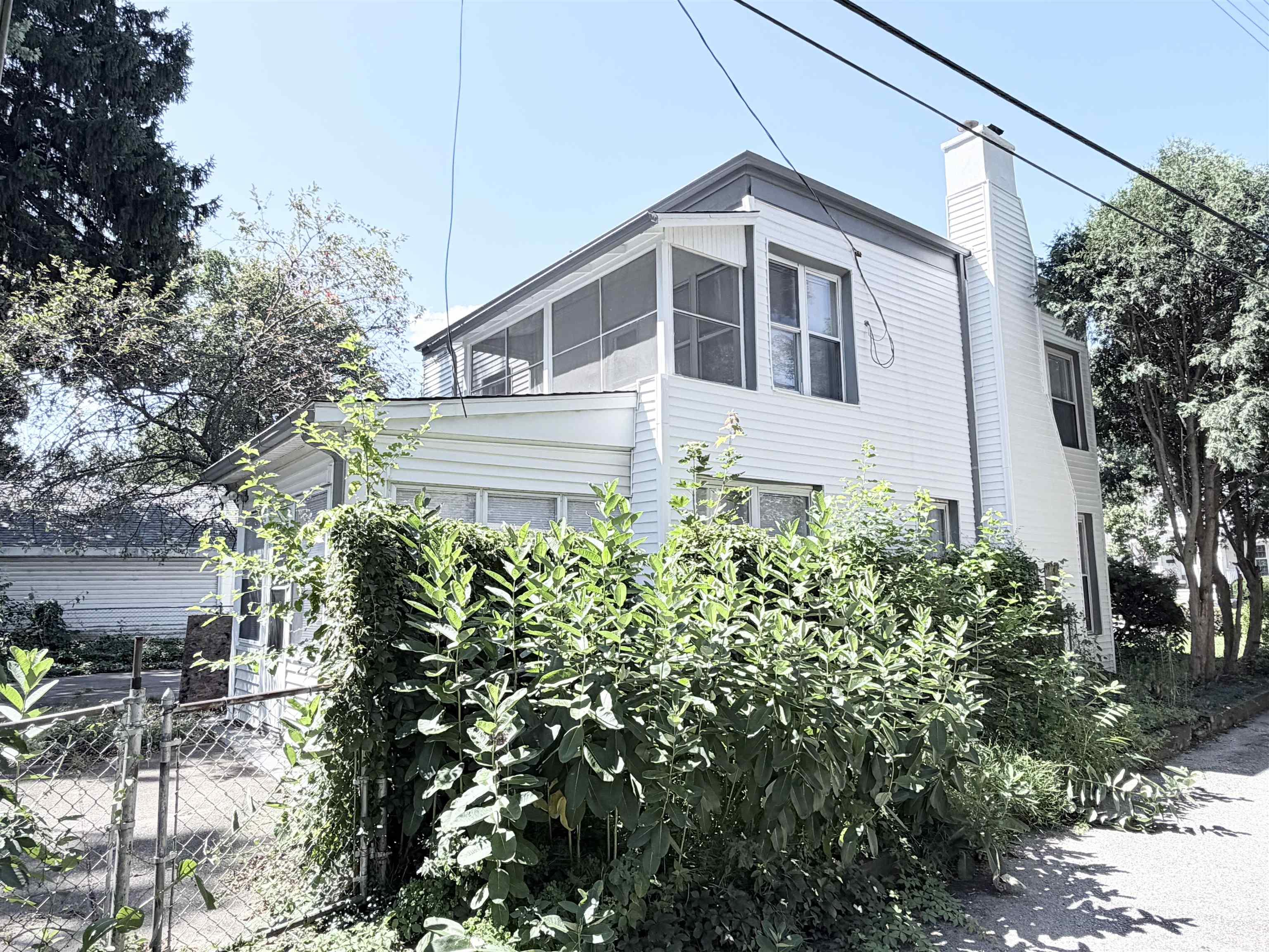 Two-story residence featuring white siding and a prominent side chimney