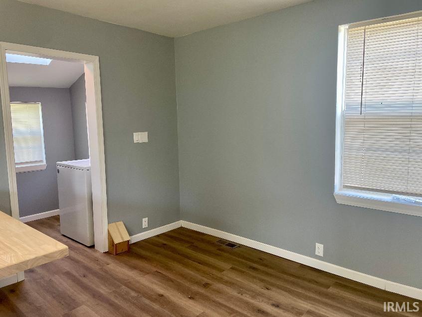 Room featuring wood-finish flooring, light grey painted walls, and white trim
