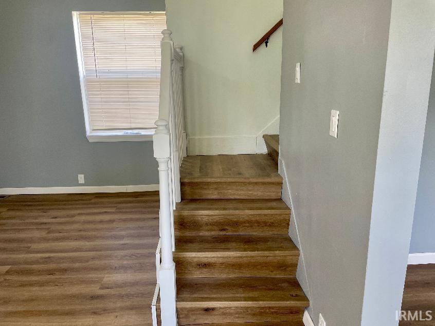 Staircase featuring wood-finish treads and white balusters