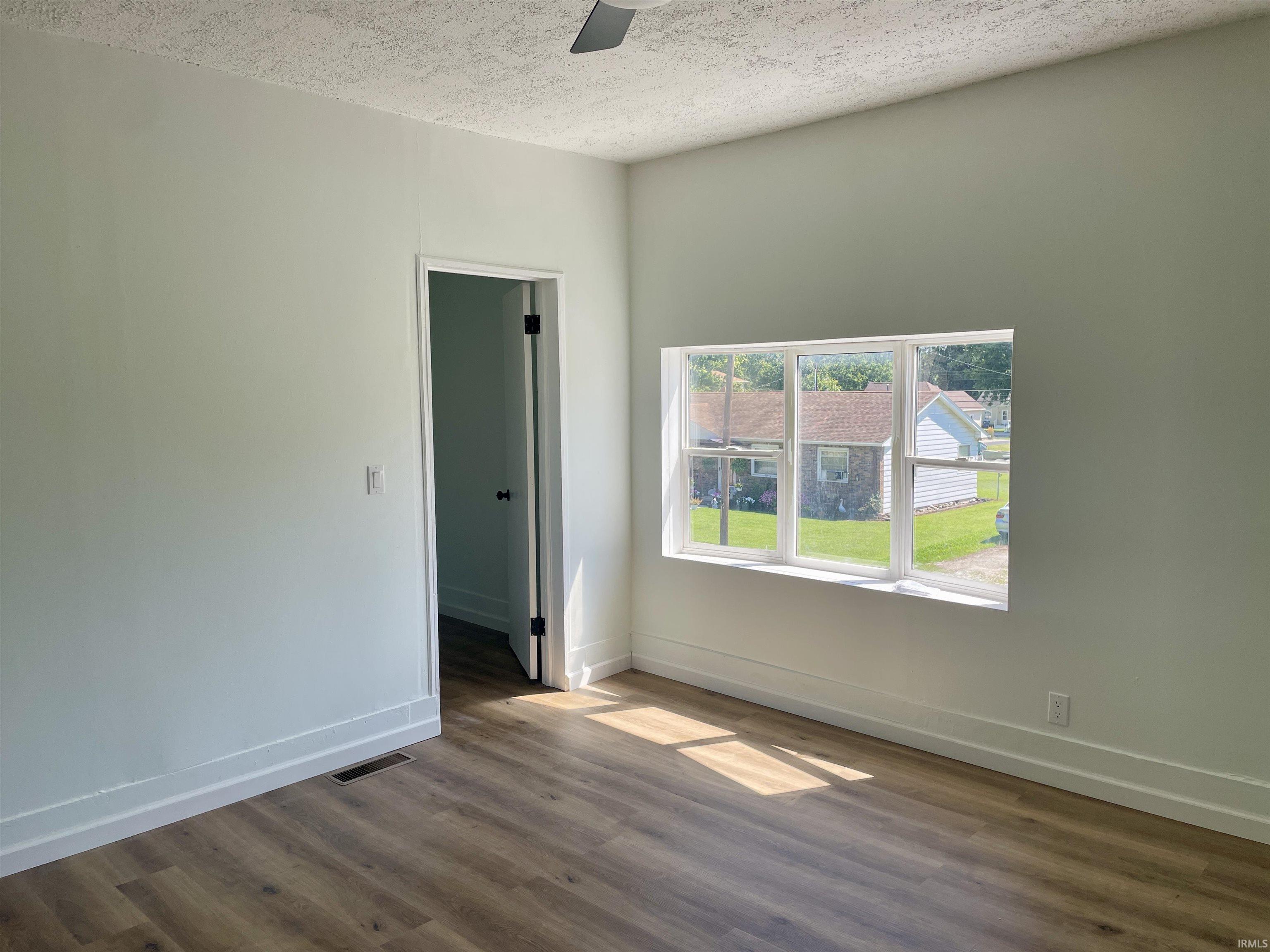Room featuring wood-finish flooring, a bright window, and a ceiling fan