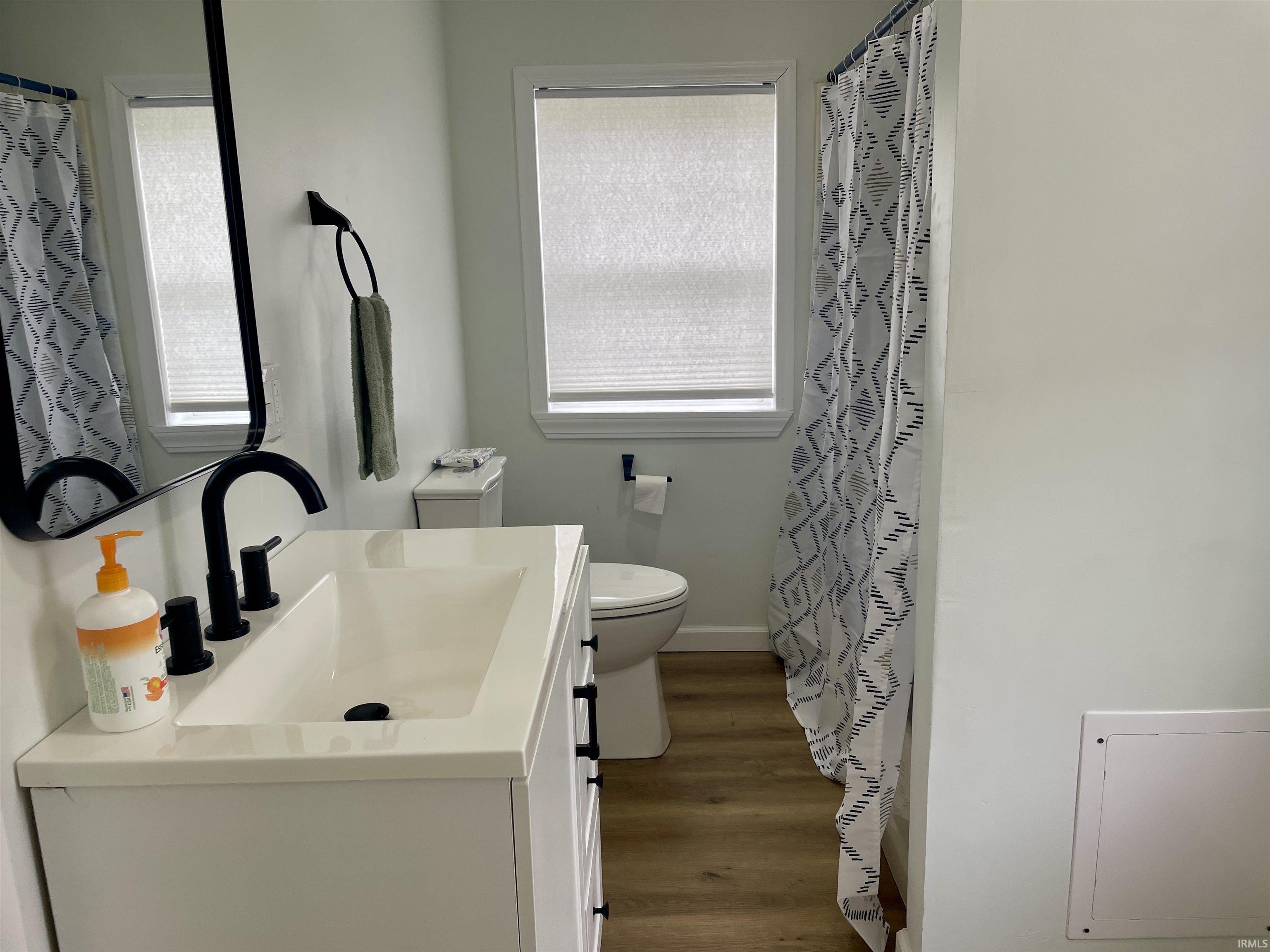 Bathroom featuring a white vanity with integrated sink, matte black faucet, and coordinating mirror