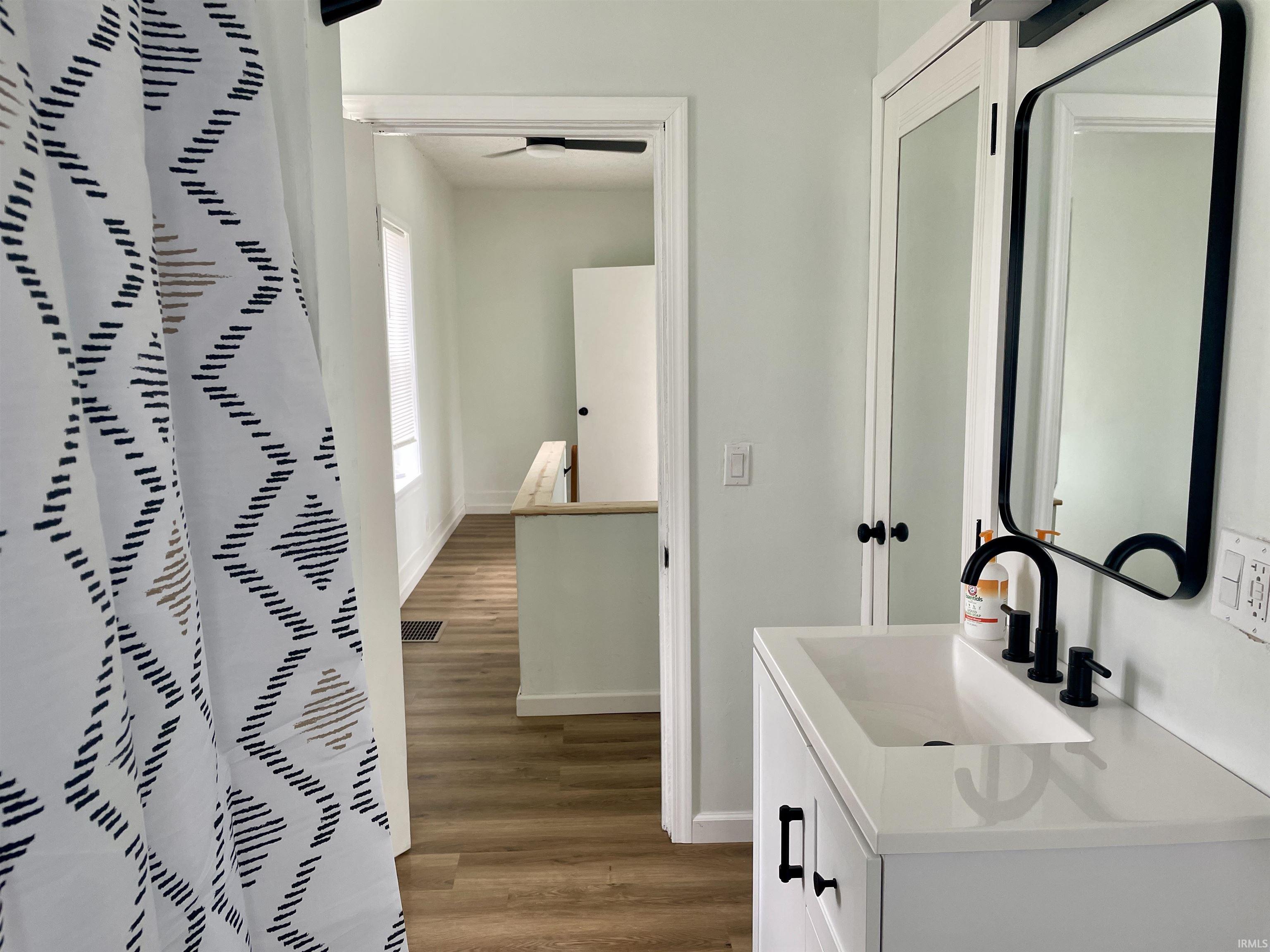 Bathroom vanity featuring a white rectangular undermount sink, black wall-mounted mirror, and matte black fixtures