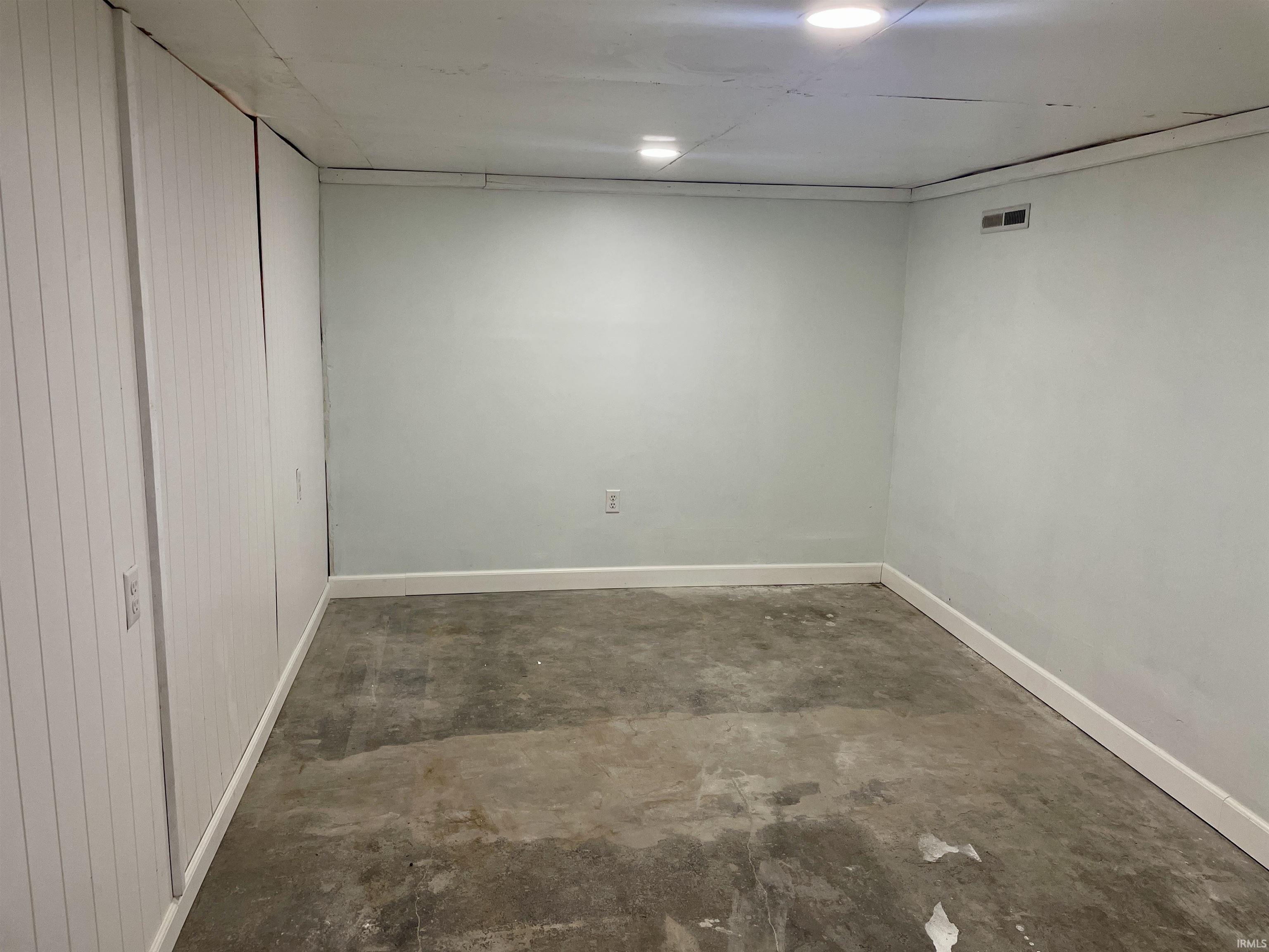 Interior space featuring light-toned walls, recessed lighting, white baseboards, and a concrete floor