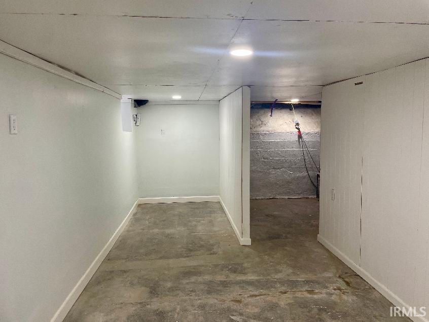 Finished basement area featuring recessed lighting, white painted walls, and concrete flooring